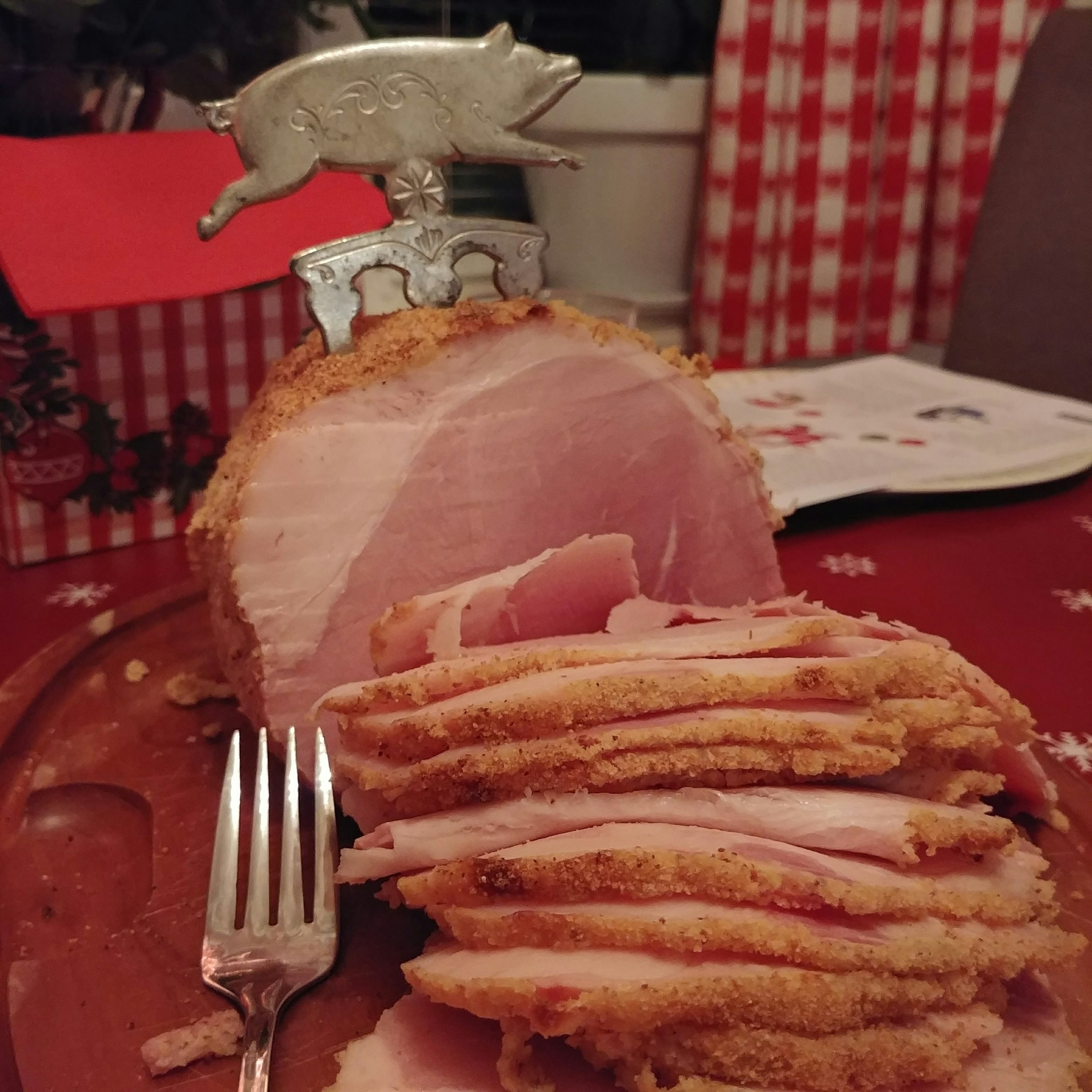 Jamón en rodajas sobre una mesa festiva con un soporte de cuchillo en forma de cerdo