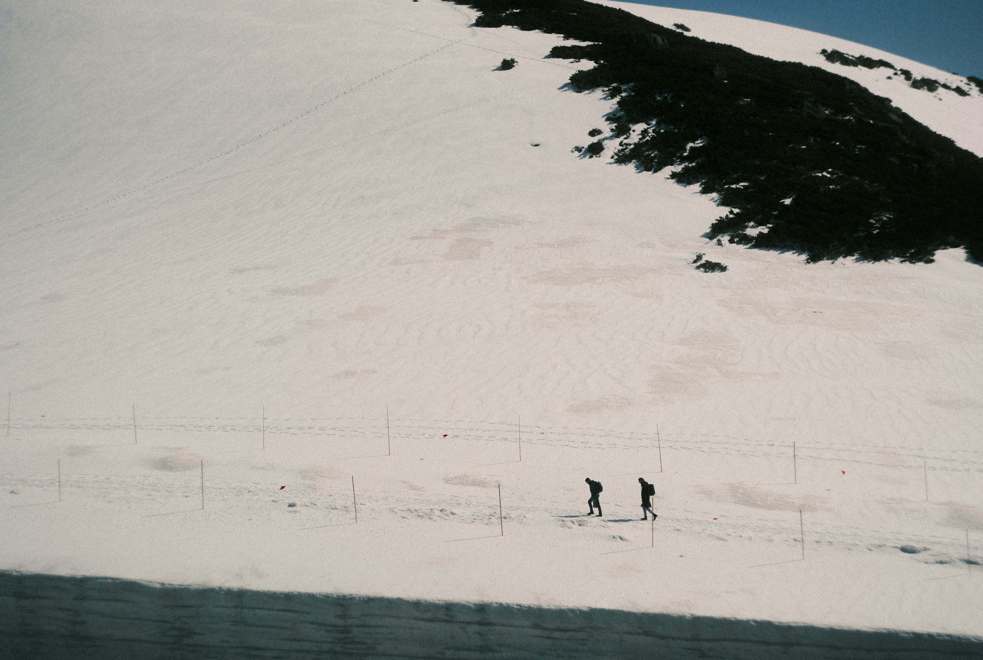 雪に覆われた斜面を歩く二人の登山者