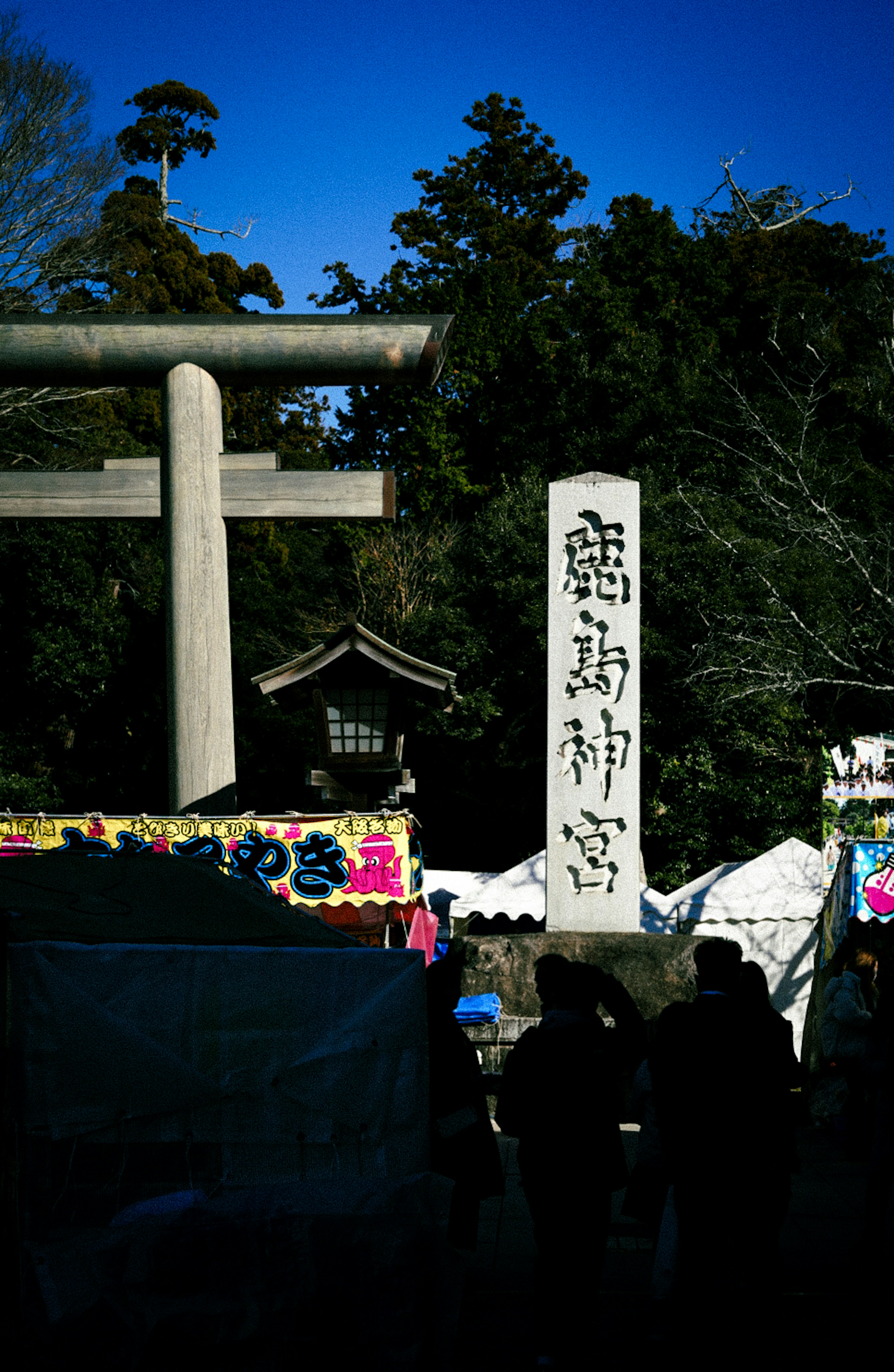 神社の鳥居と石碑が映る風景 人々が集まる賑やかな光景