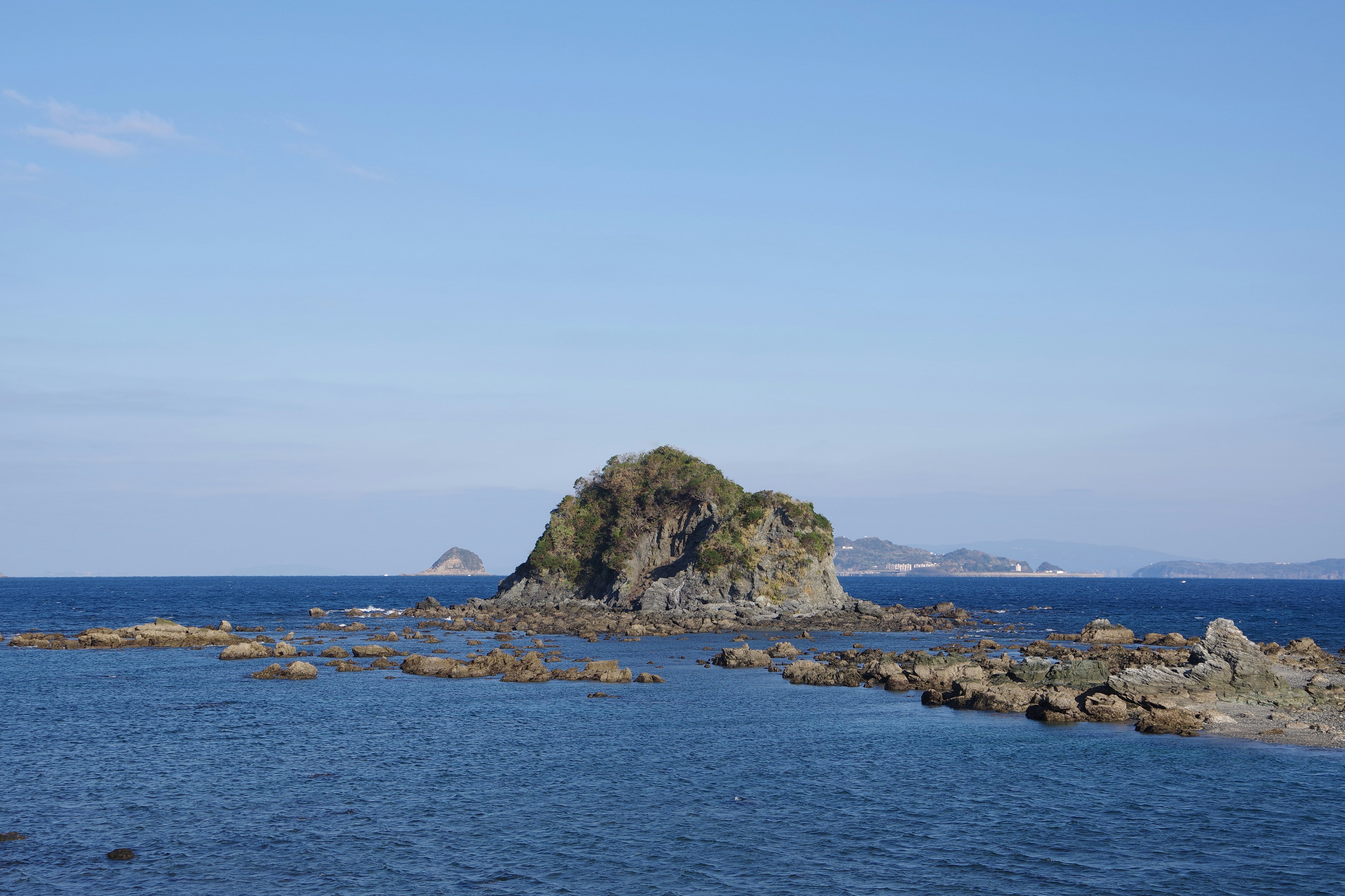 Small island surrounded by blue sea and rocks