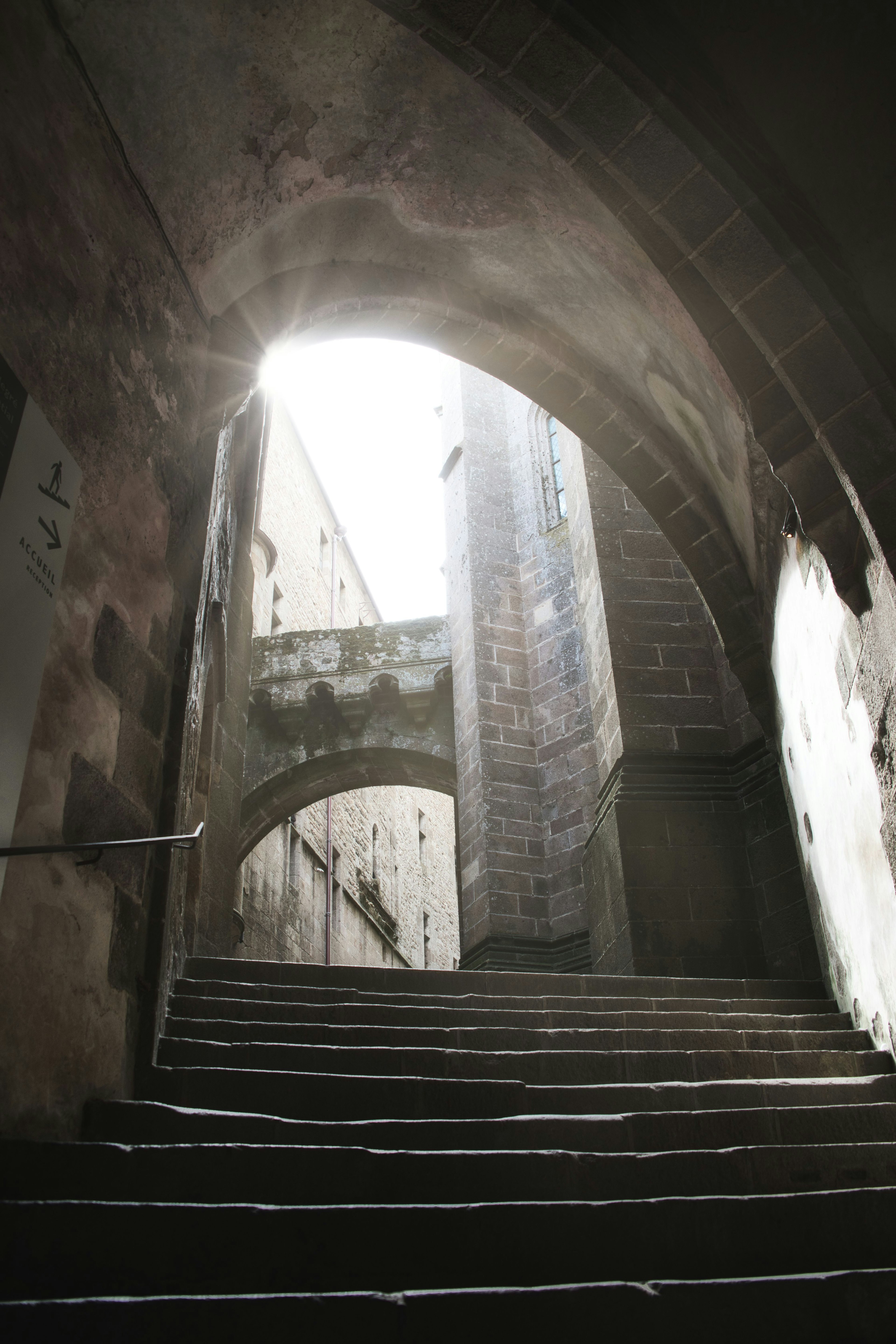 Ein gewölbter Durchgang mit Licht, das oben in eine Treppe strömt