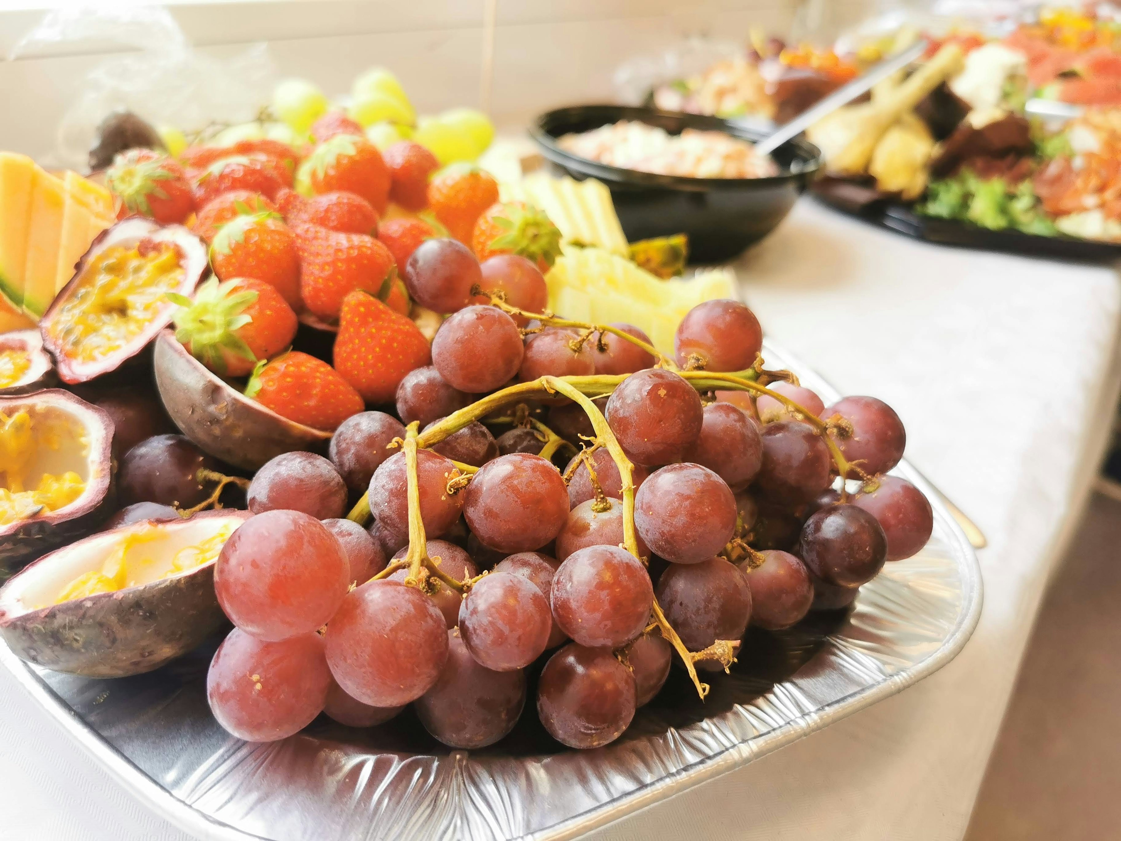 A platter of assorted colorful fruits including grapes strawberries and passion fruit