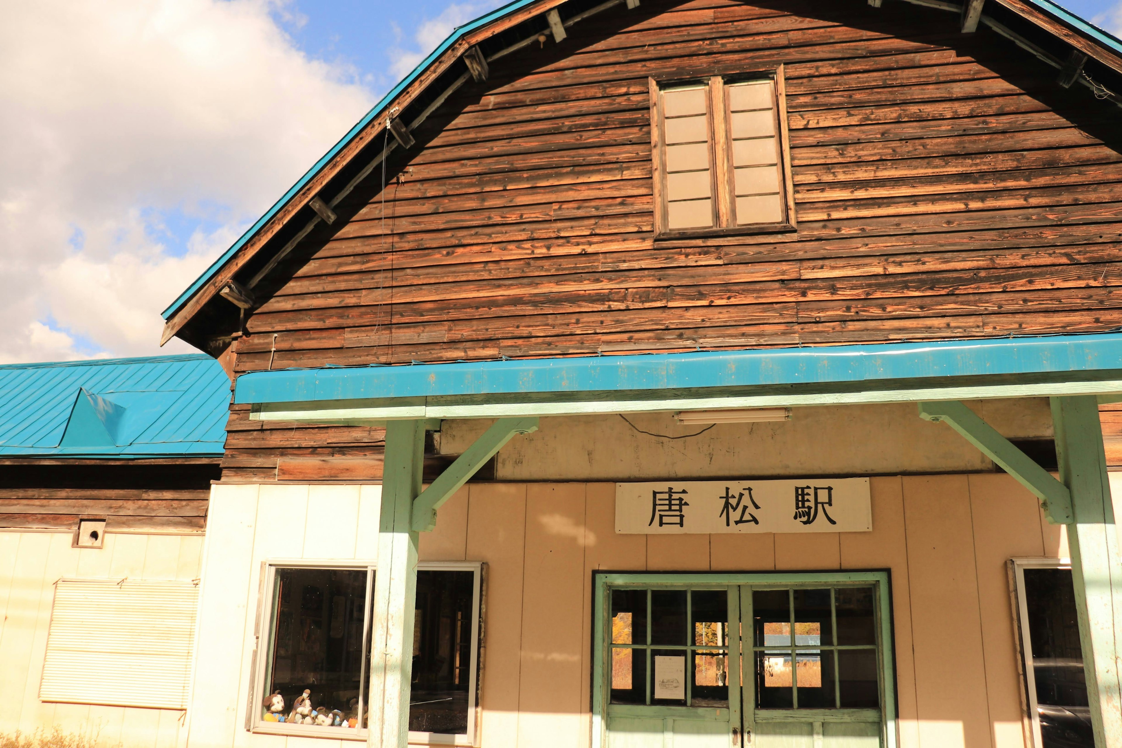 Exterior of an old wooden train station featuring windows a blue roof and white walls