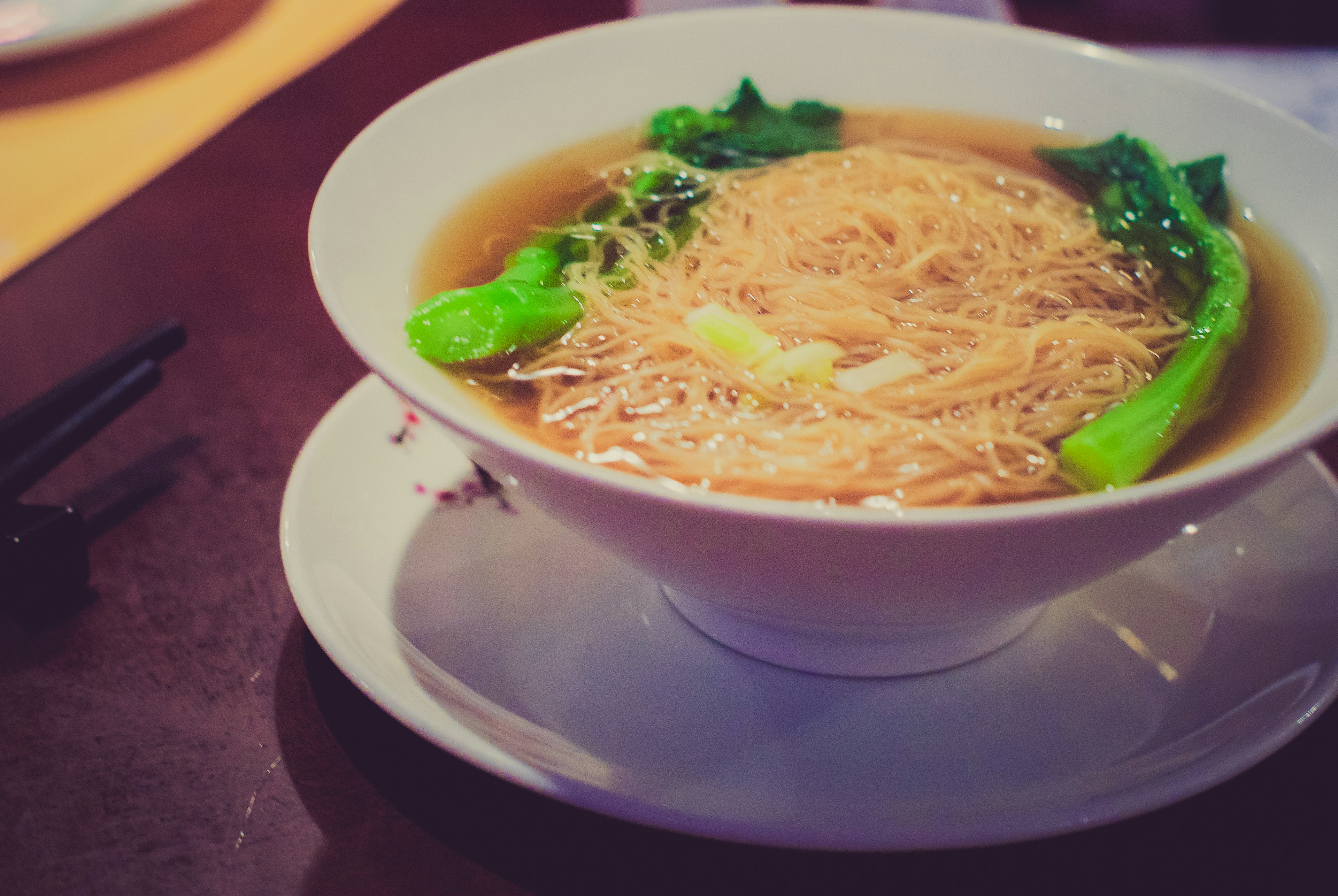 ラーメンが入った白いボウルに野菜がトッピングされている