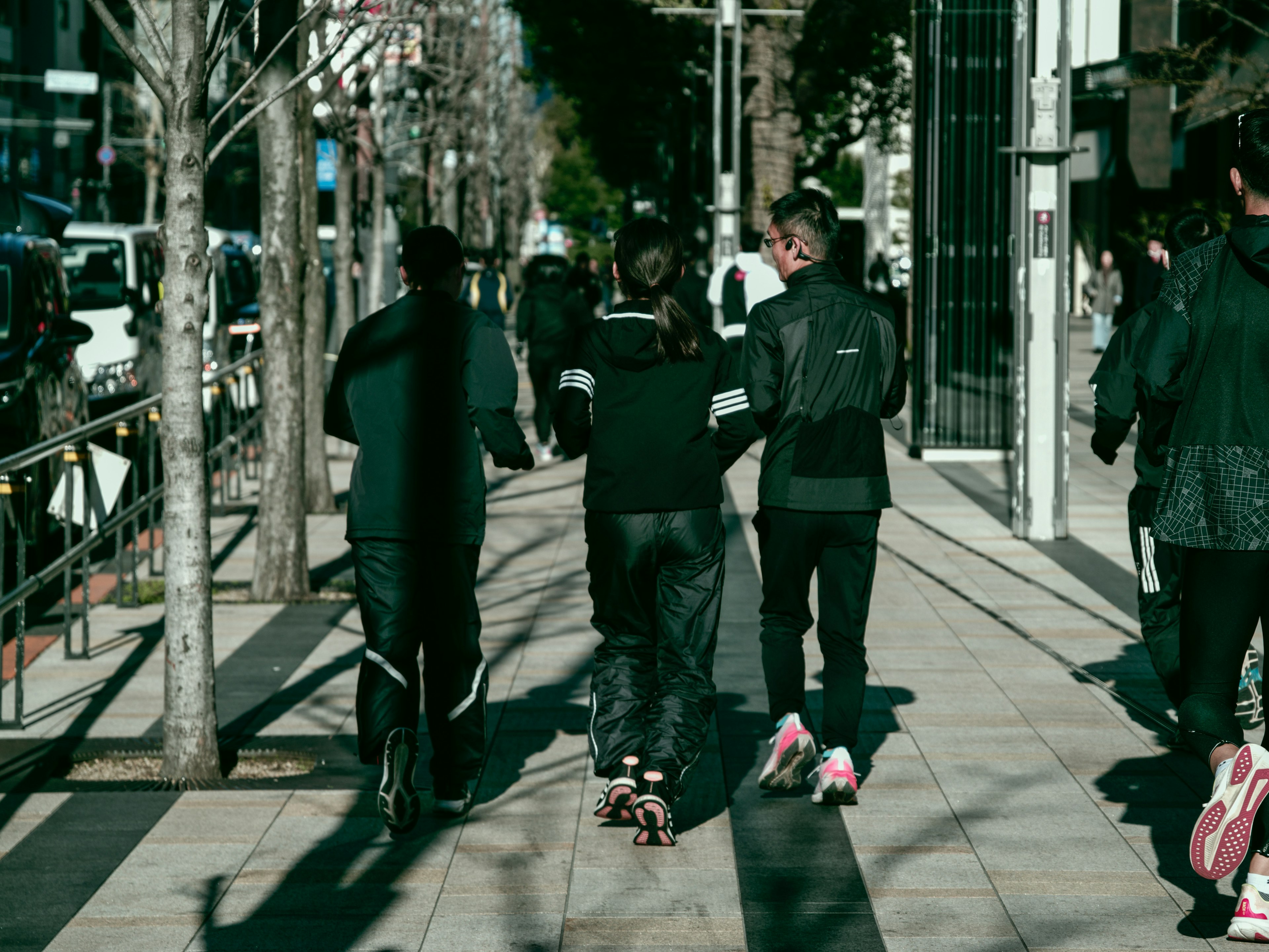 Junge Leute gehen auf einem Bürgersteig in der Stadt und tragen grüne und schwarze Kleidung