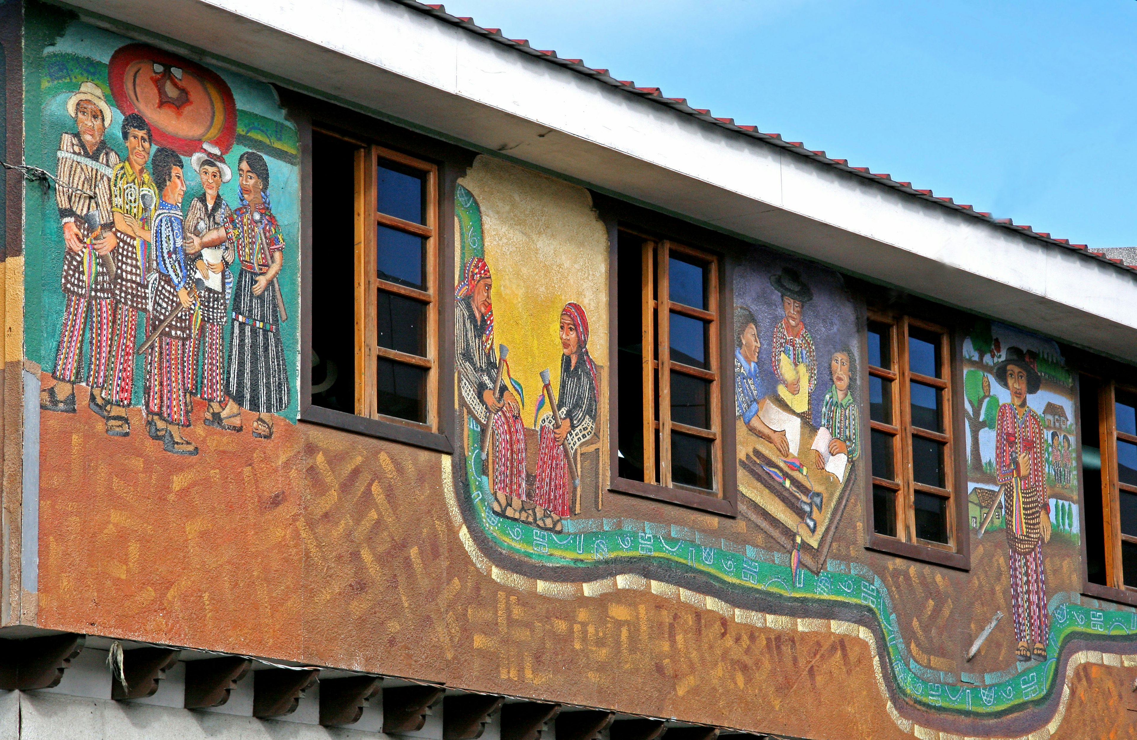 Colorful mural depicting various scenes of agriculture and culture on a building exterior with windows