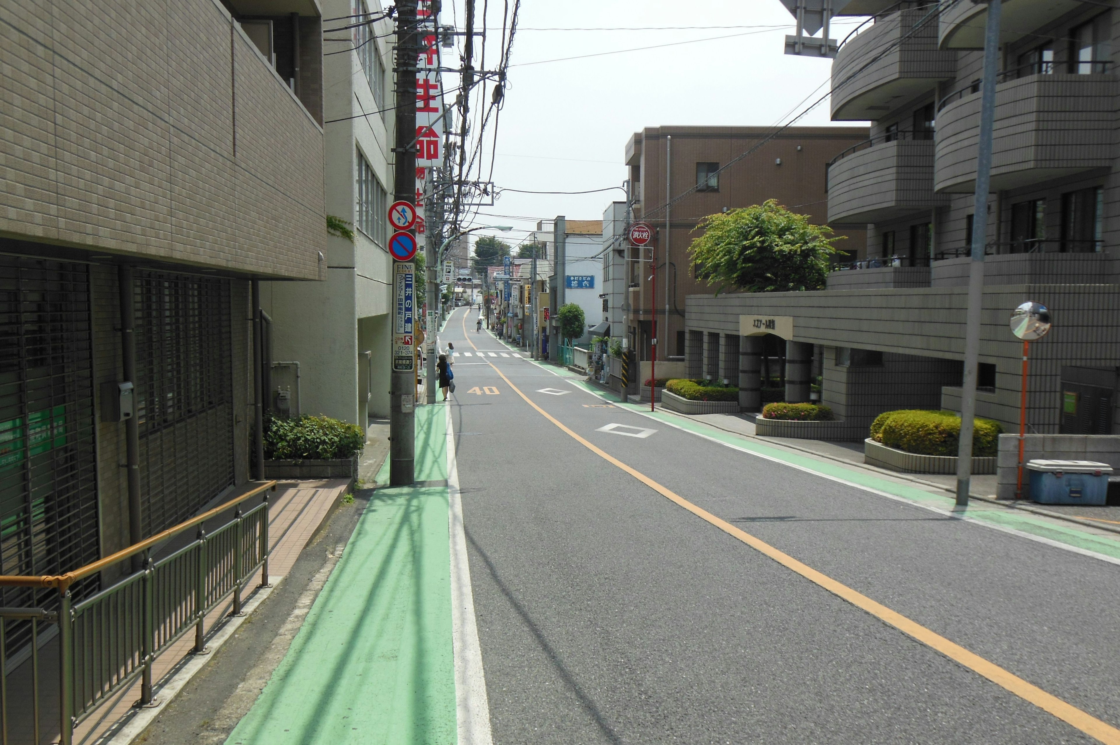 Quiet street scene in Japan featuring green bike lane and concrete buildings