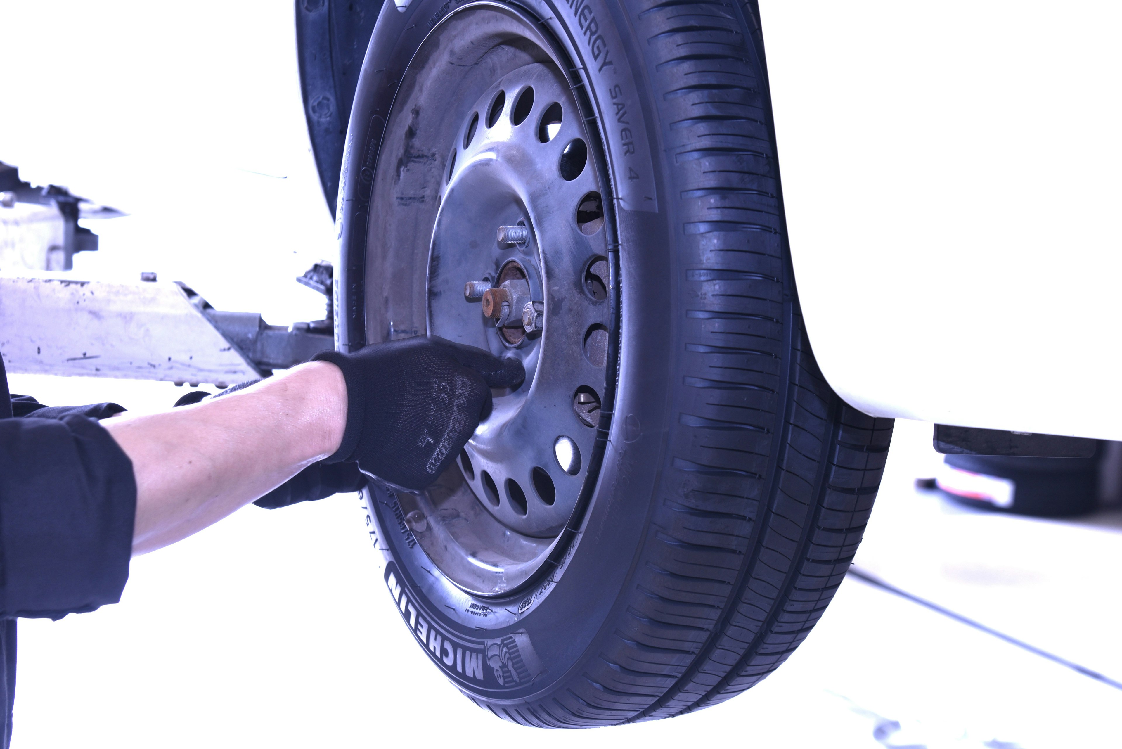 A technician inspecting a car tire with a gloved hand