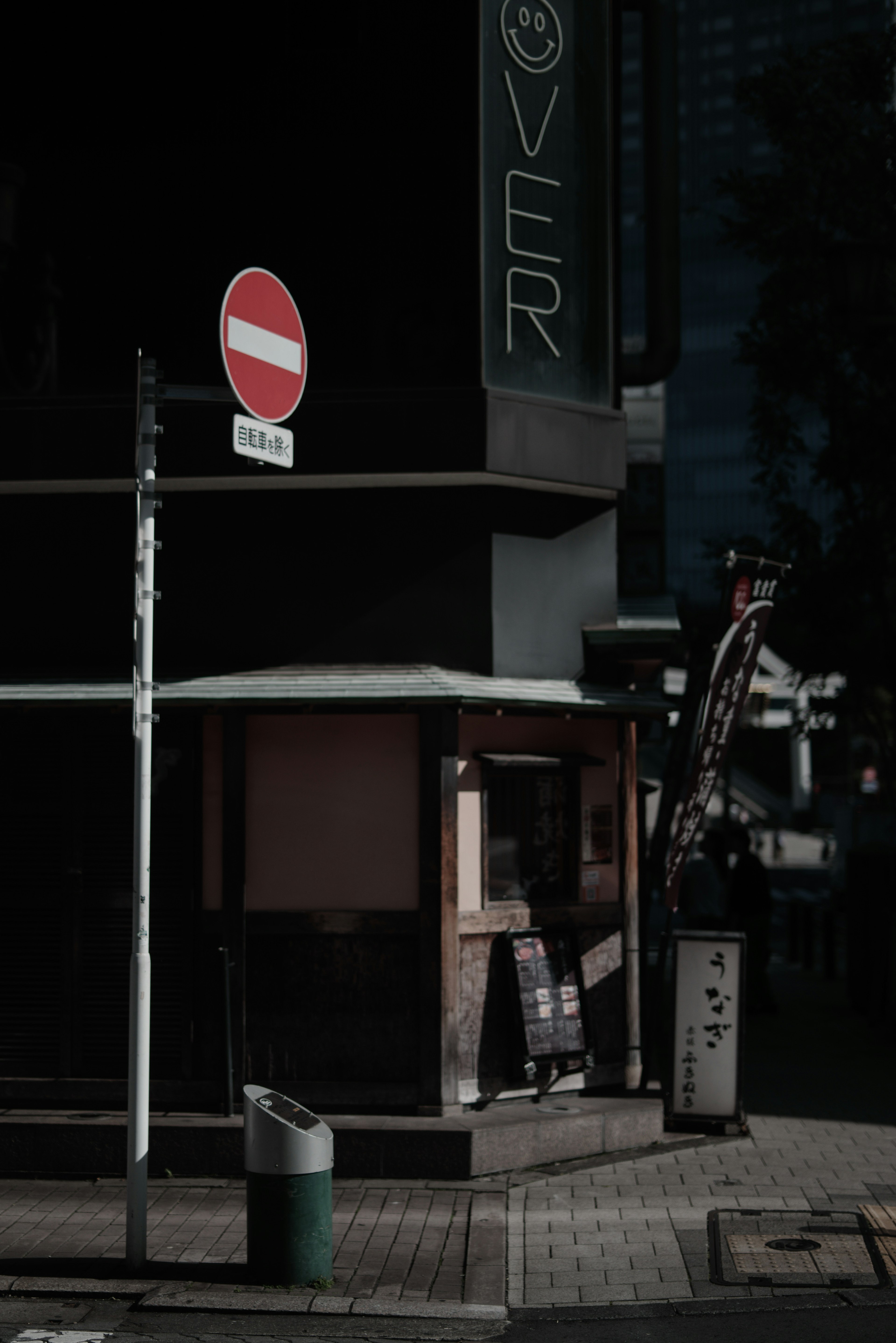 暗い路地にある飲食店の外観と赤い禁止標識