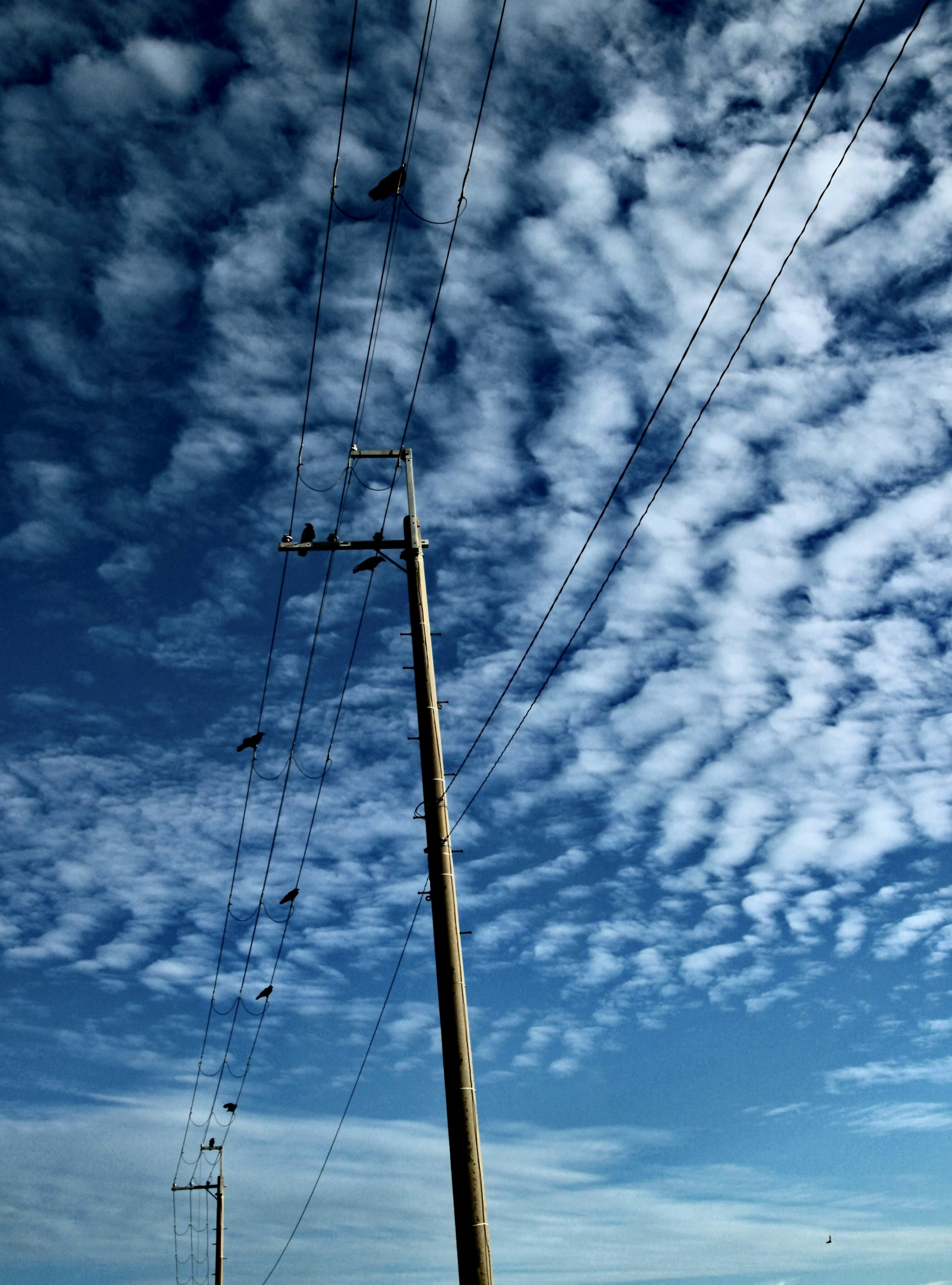 Un paysage avec un poteau électrique contre un fond de ciel bleu et de nuages épars