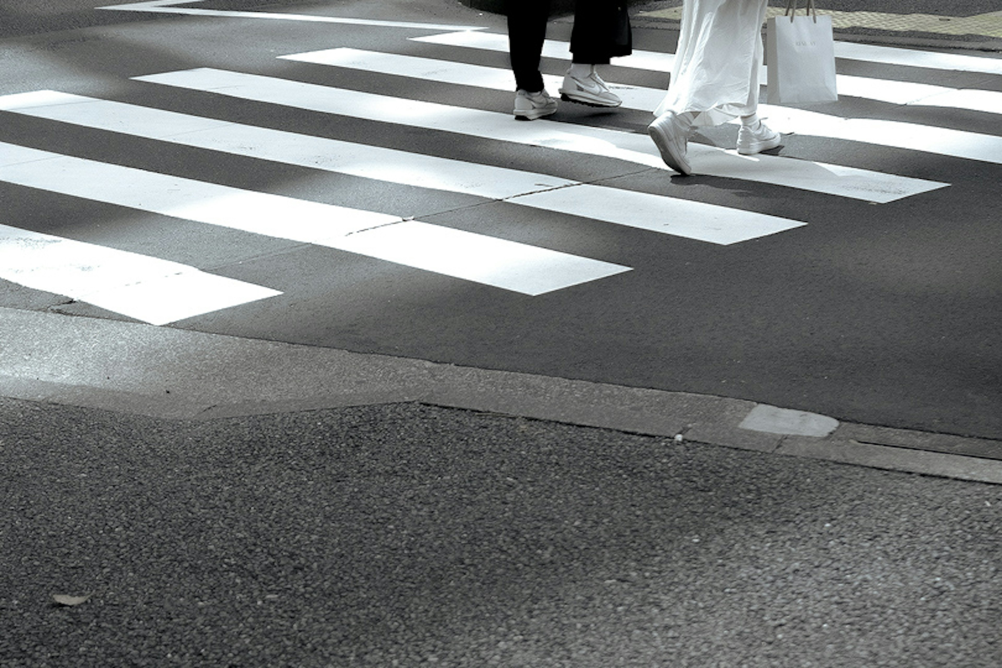 Feet of people crossing a white crosswalk