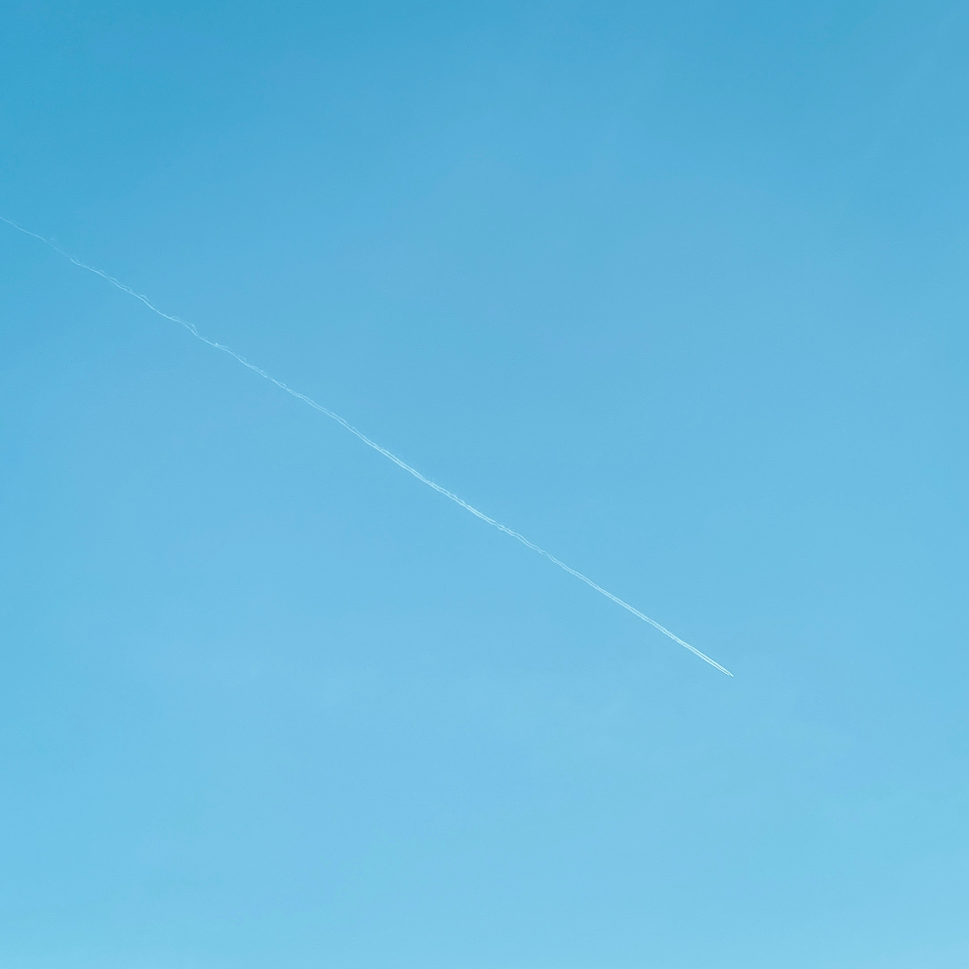 青空に白い飛行機雲が横切る景色