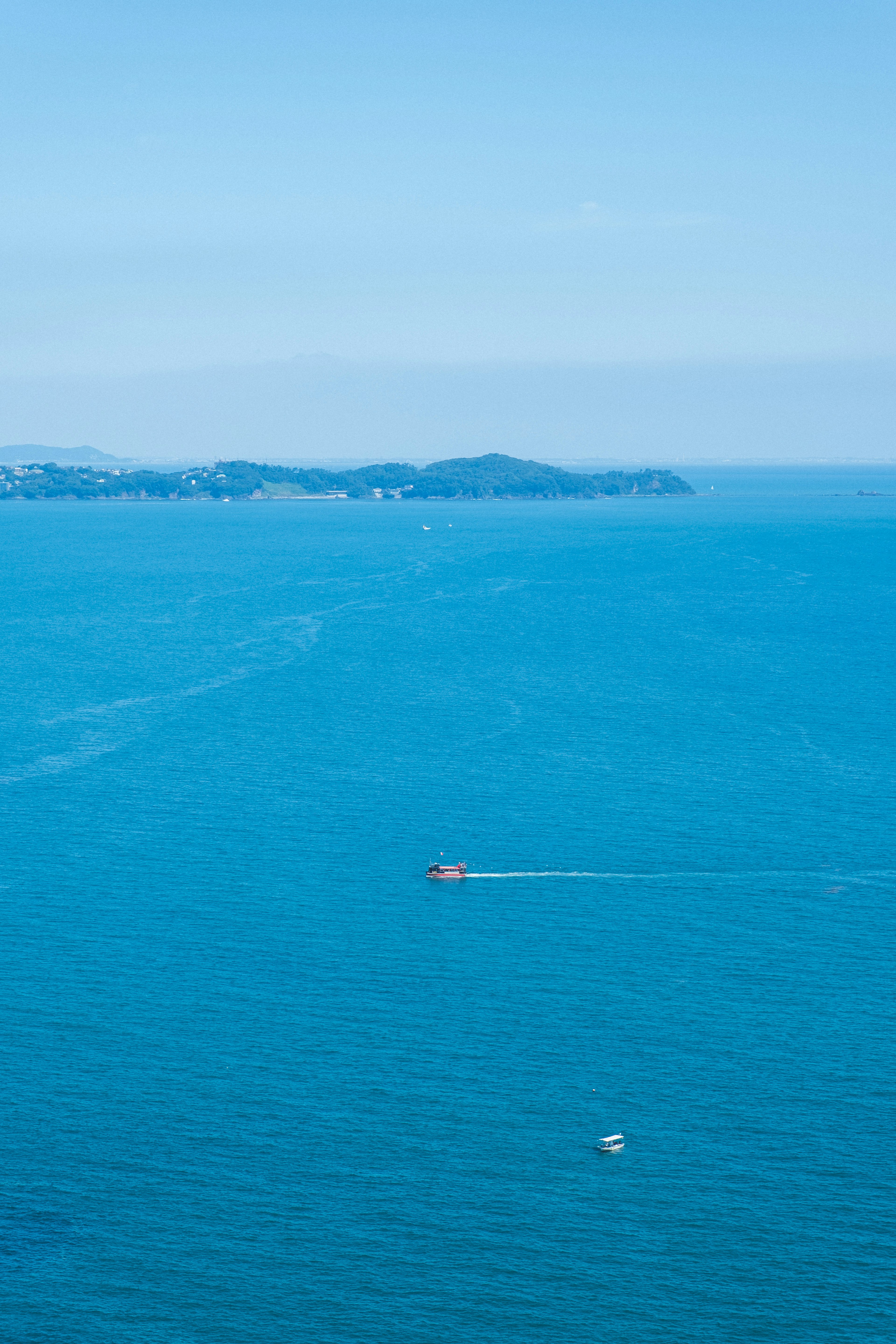 A panoramic view of a blue ocean with a small boat