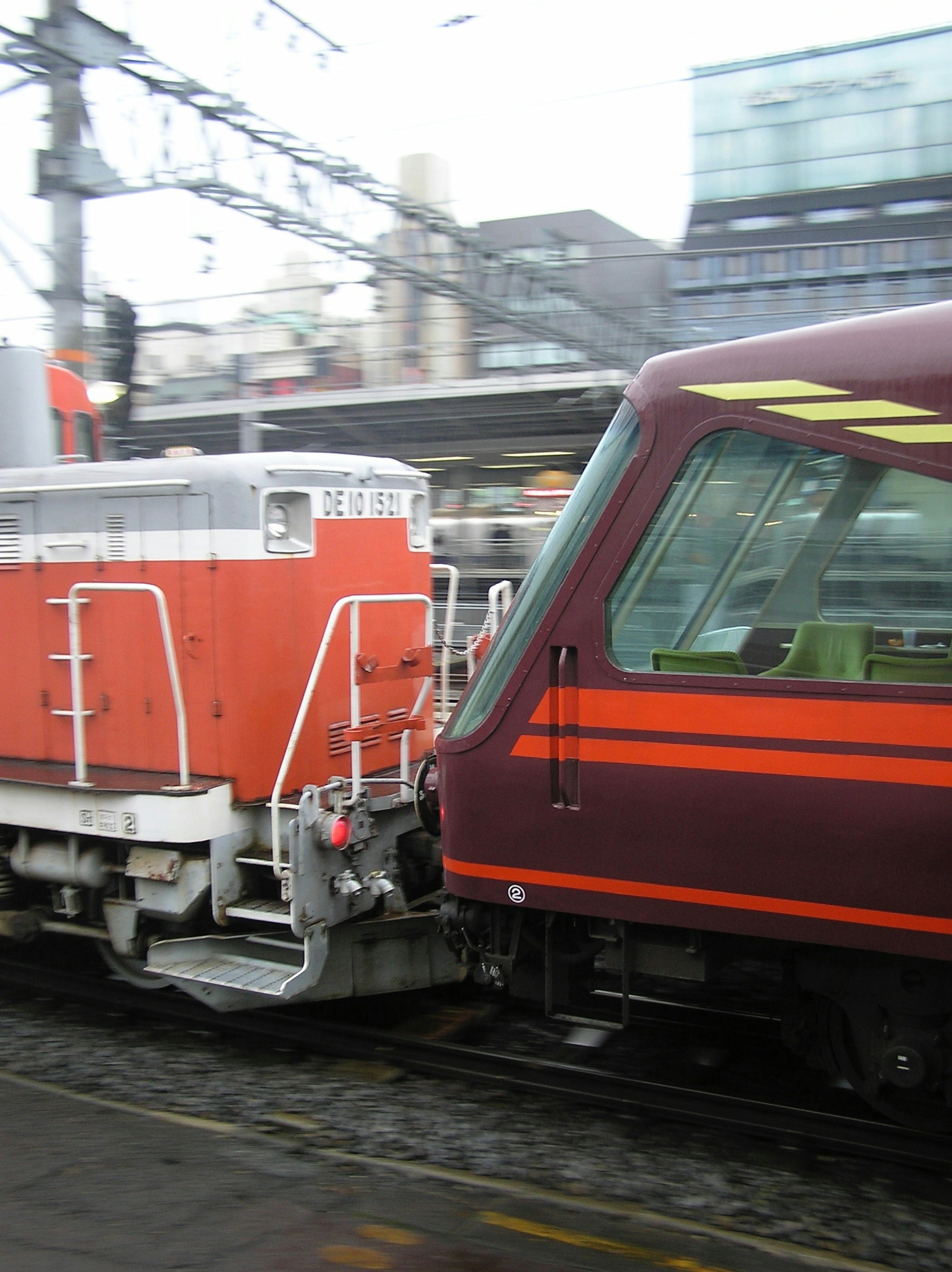 Locomotora naranja y tren morado en una estación de cerca