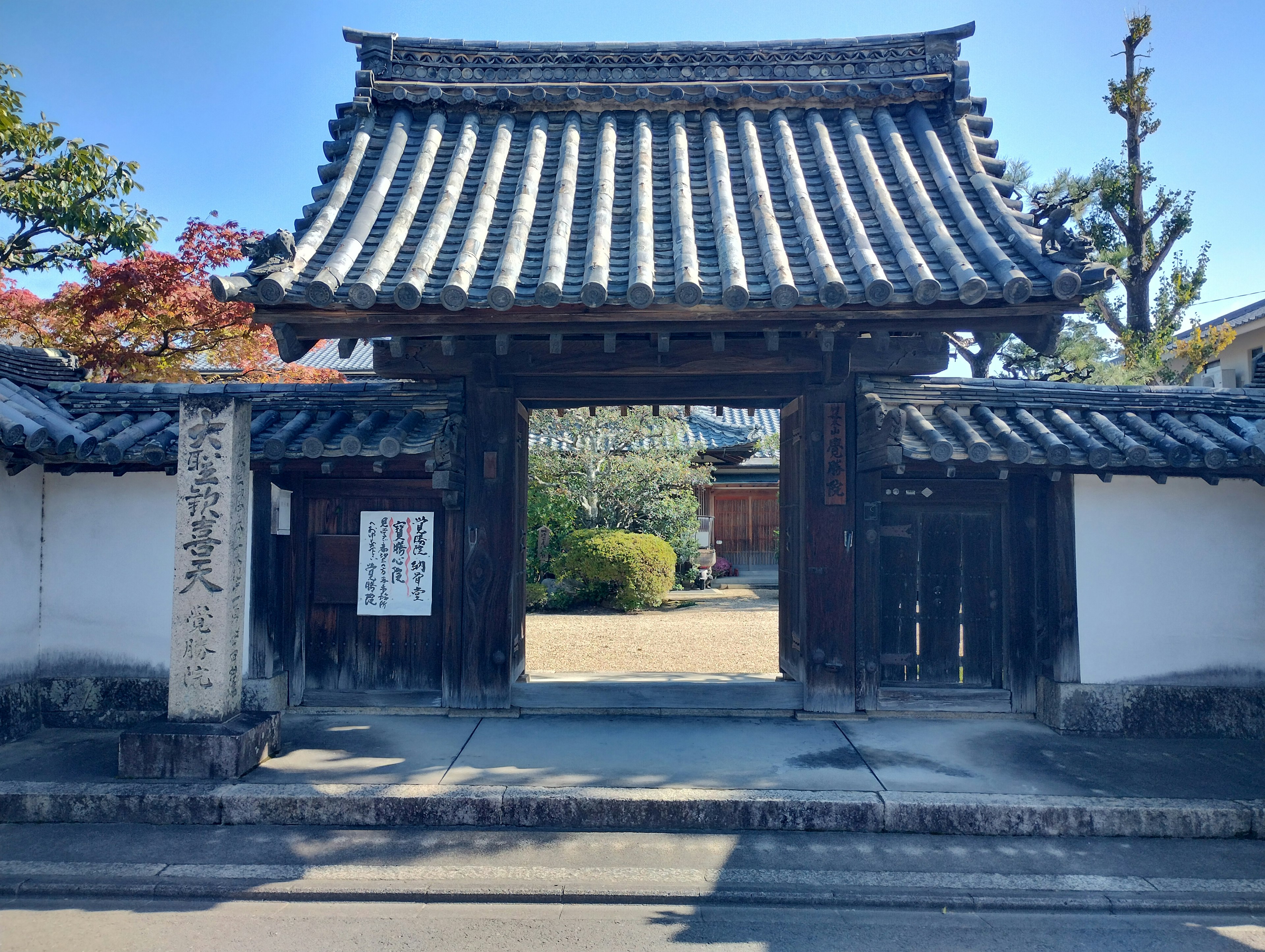 Traditional Japanese gate with unique roof design and surrounding greenery