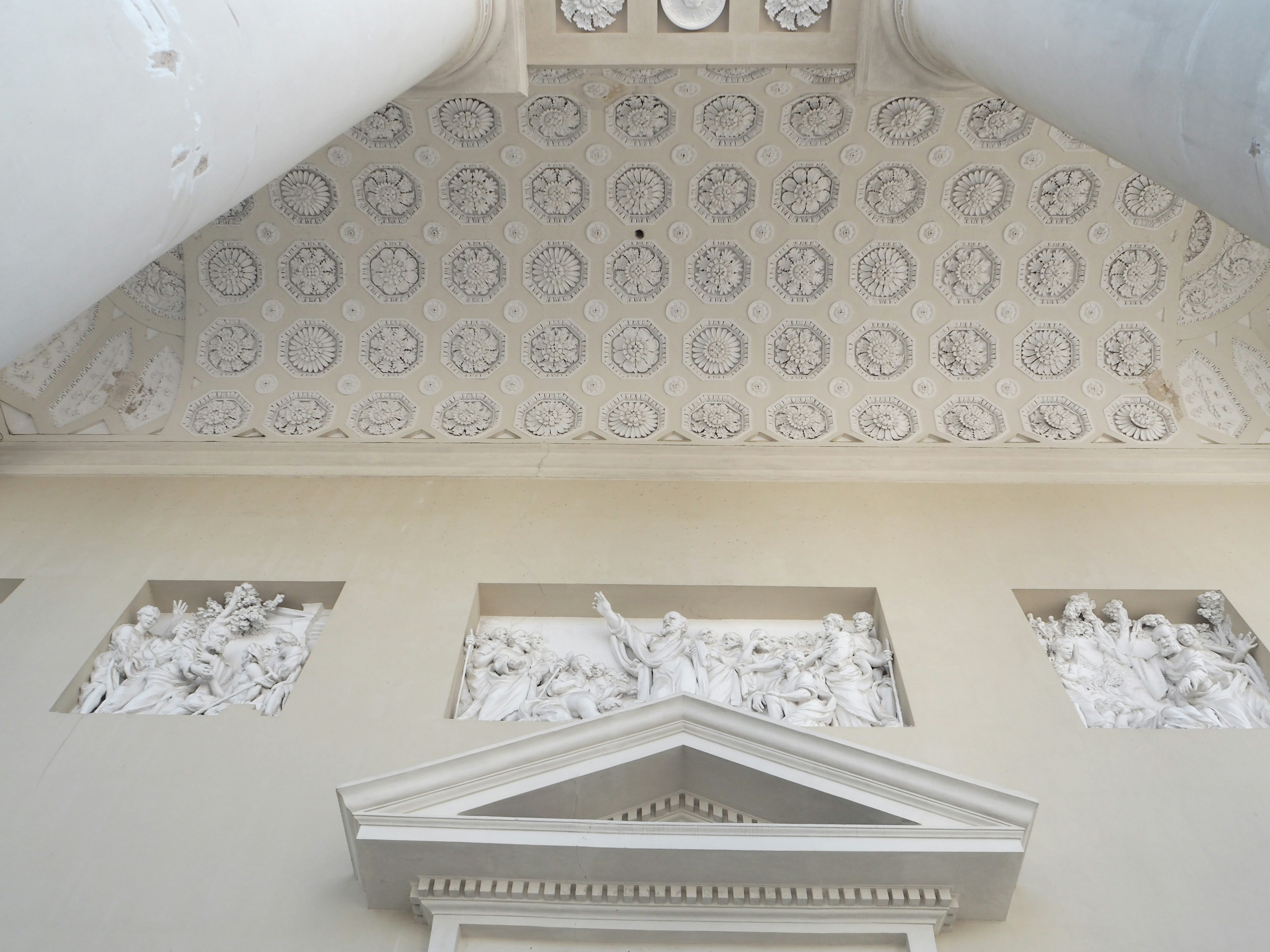 Intérieur d'un bâtiment avec un plafond décoré et des sculptures blanches