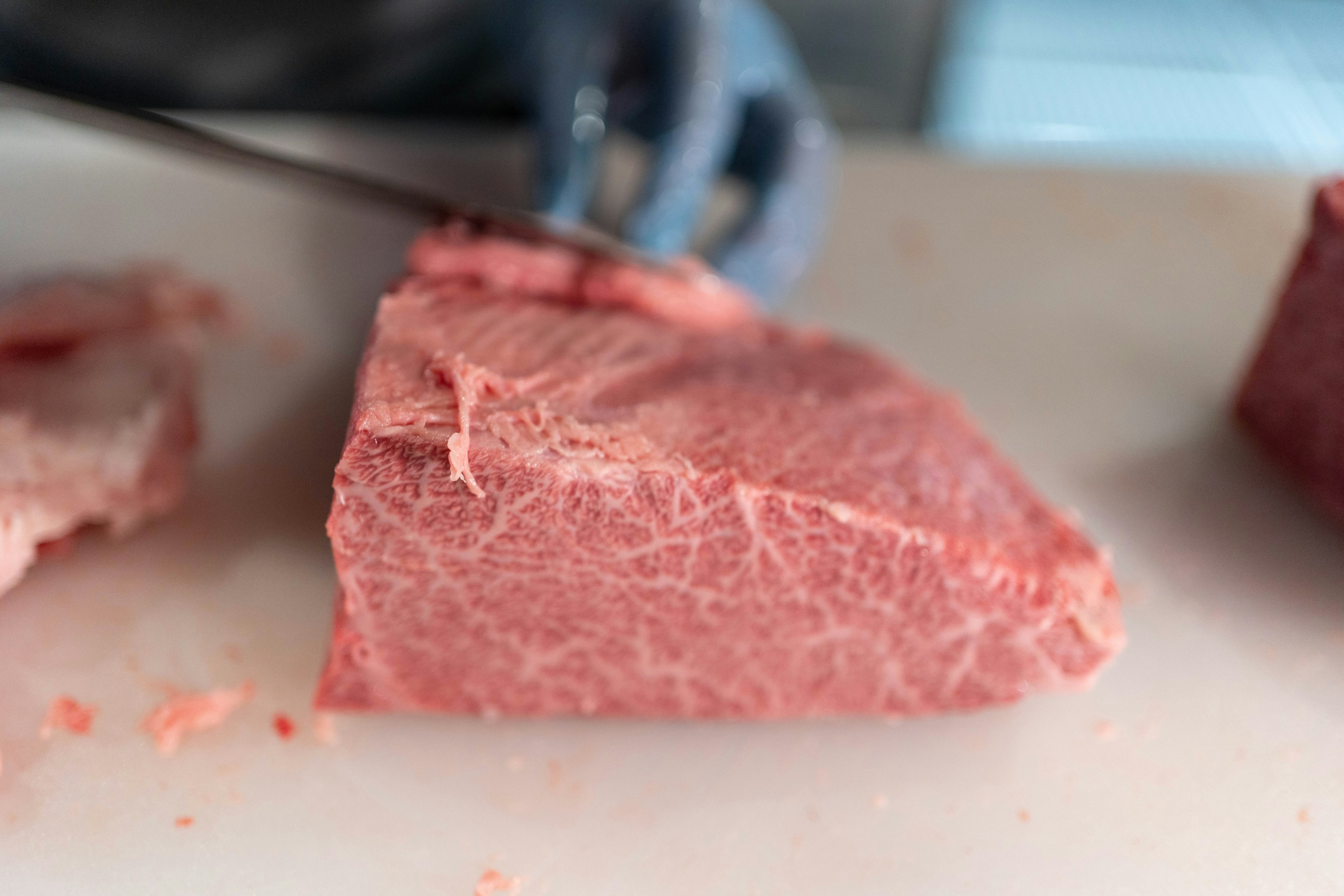 Mano cortando un trozo de carne roja veteada