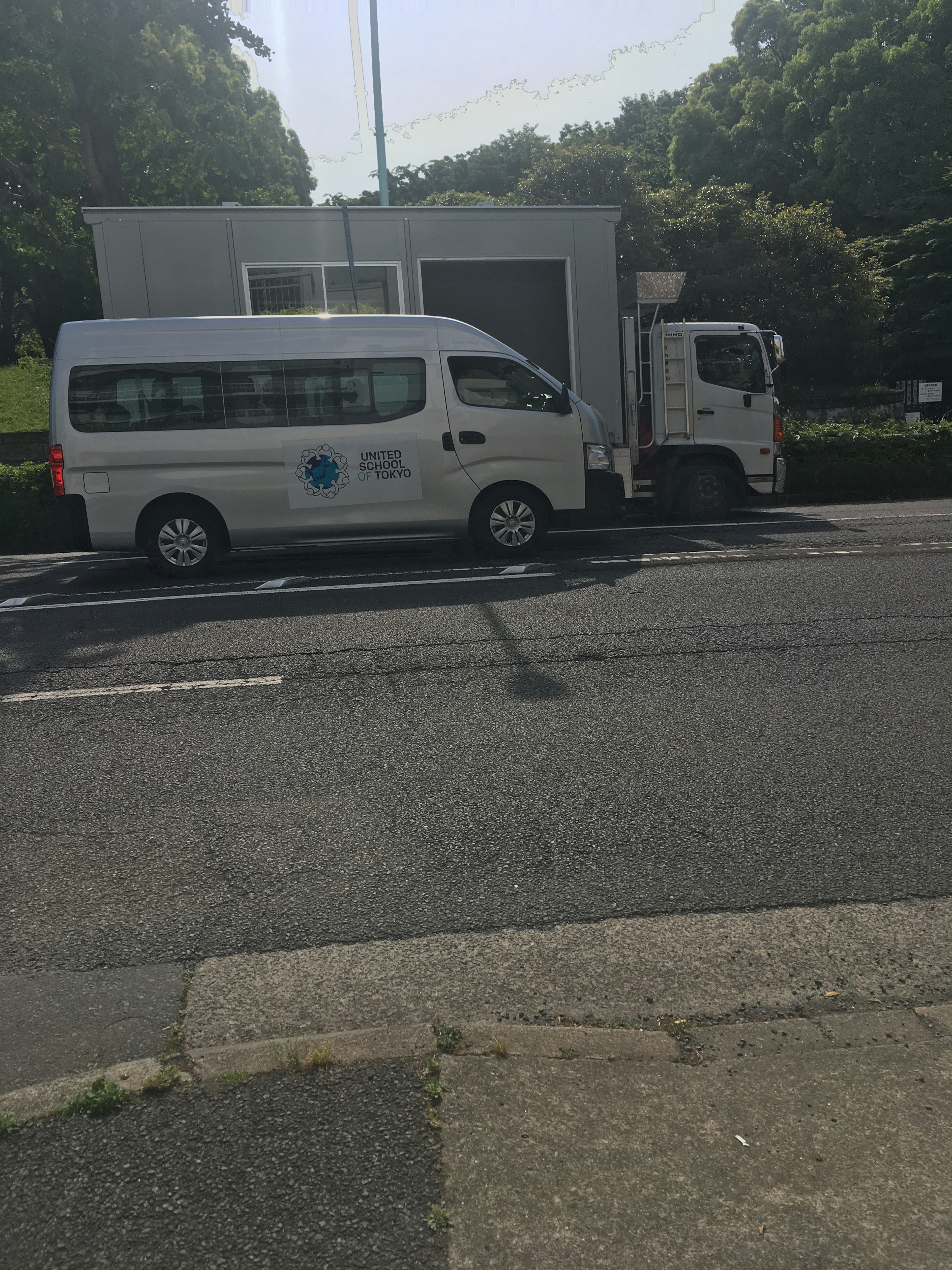 白いバンとトラックが並んで停まっている街の風景