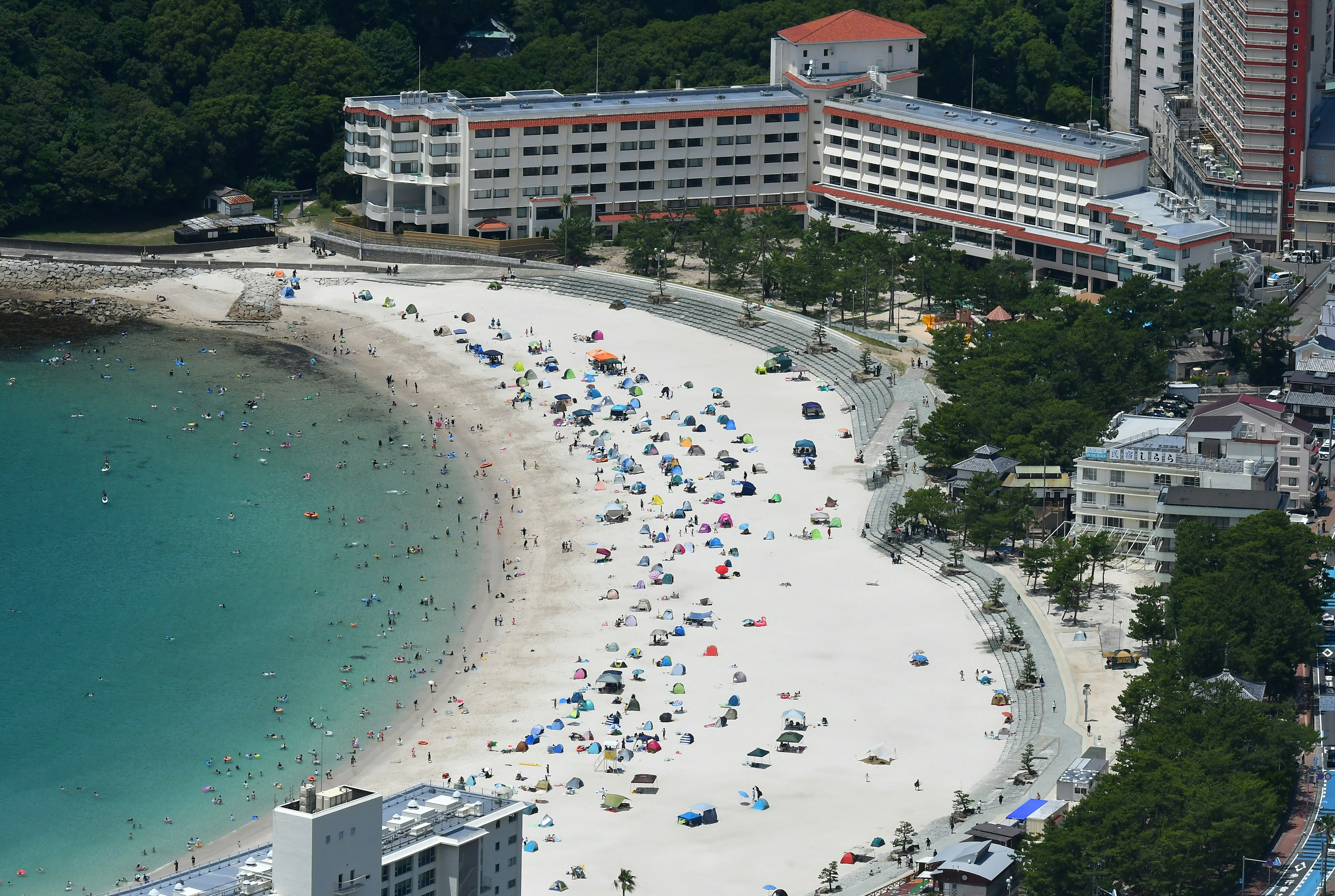 มุมมองจากอากาศของชายหาดที่สวยงามพร้อมร่มชายหาดสีสันสดใสและโรงแรมรีสอร์ท