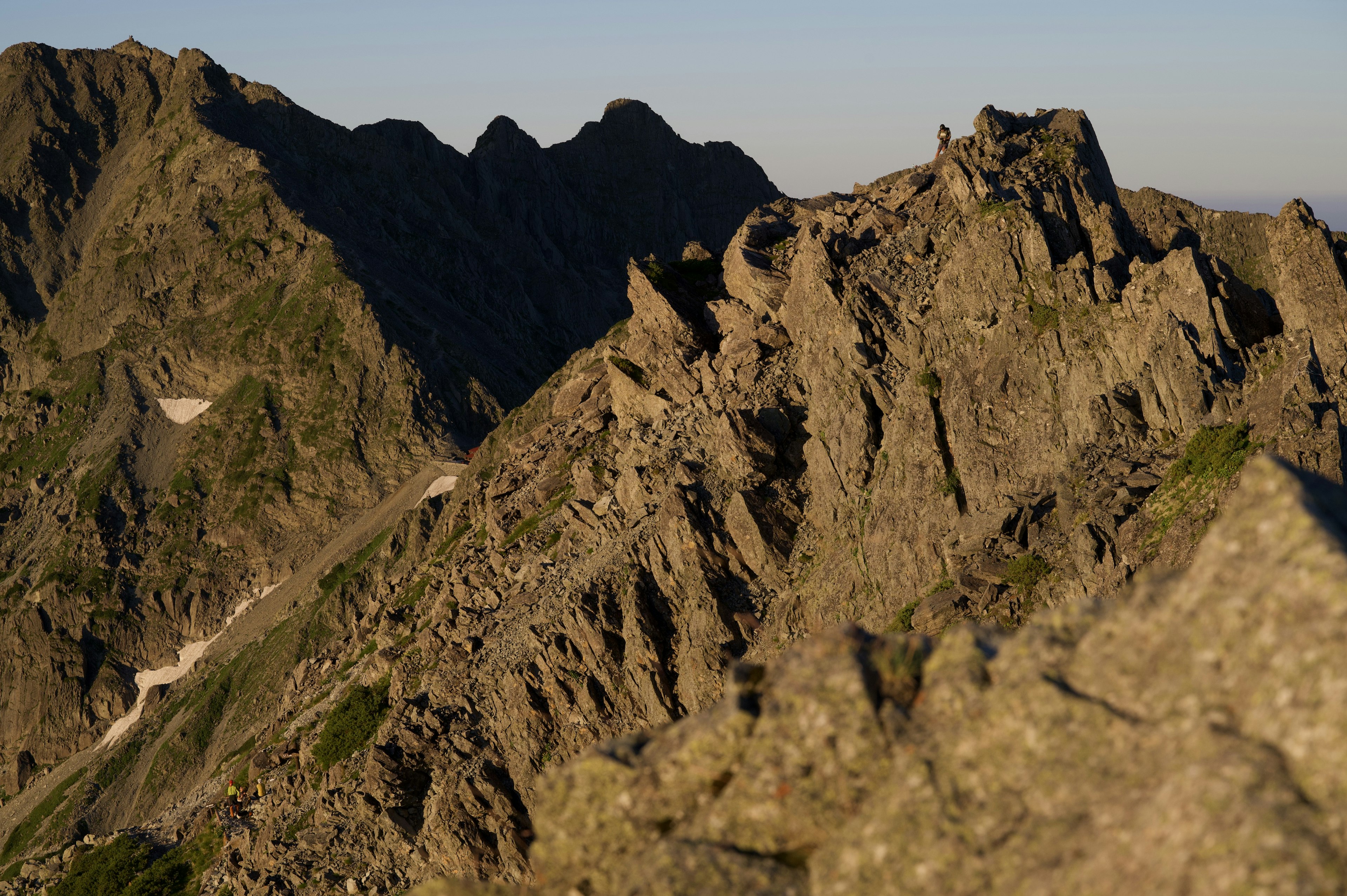 Nahaufnahme von zerklüfteten Berggipfeln, die im Licht der Abenddämmerung beleuchtet sind