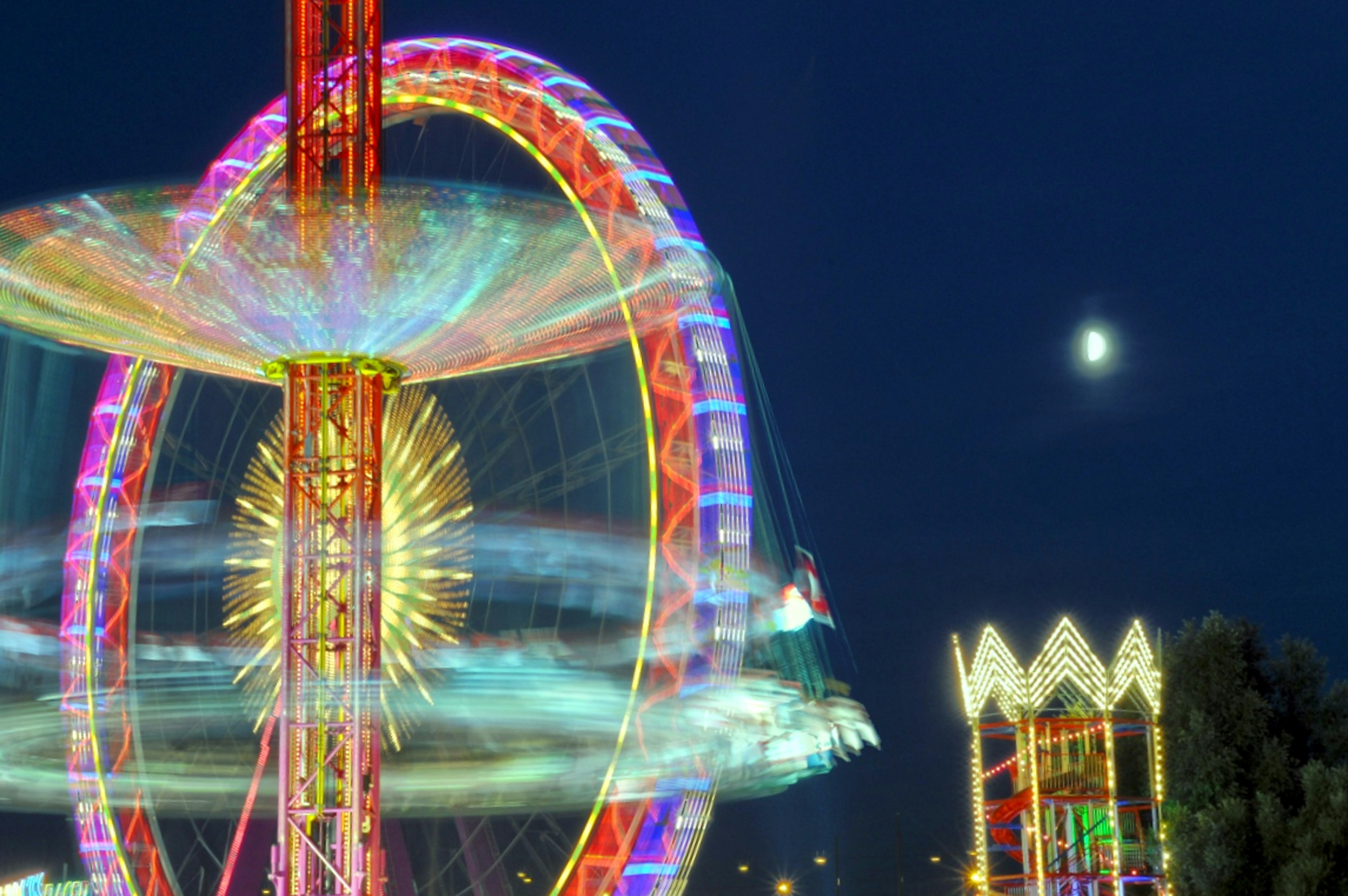 Lumières colorées d'une grande roue et d'un carrousel sous le ciel nocturne