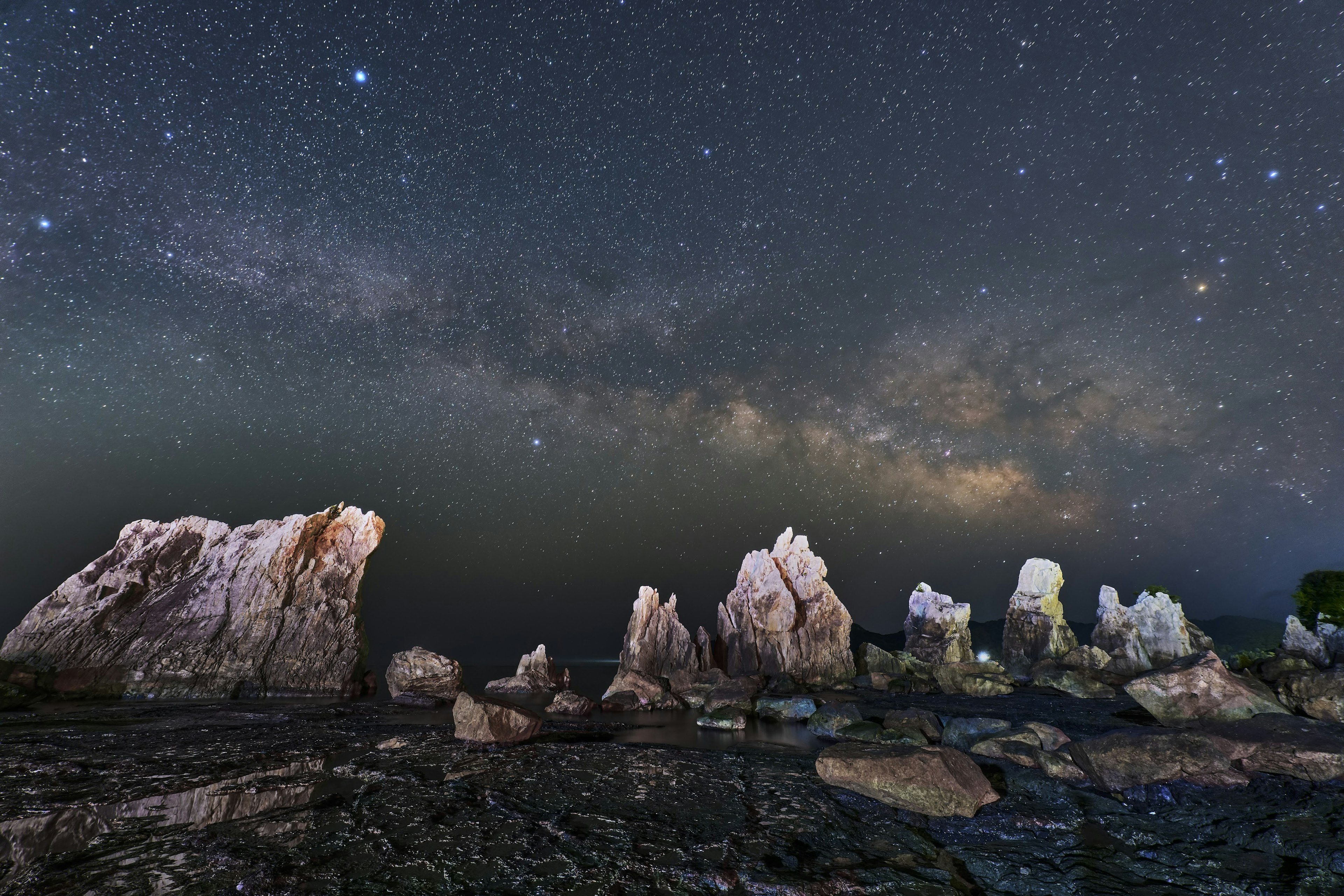 Un paisaje hermoso de formaciones rocosas bajo un cielo estrellado con la Vía Láctea