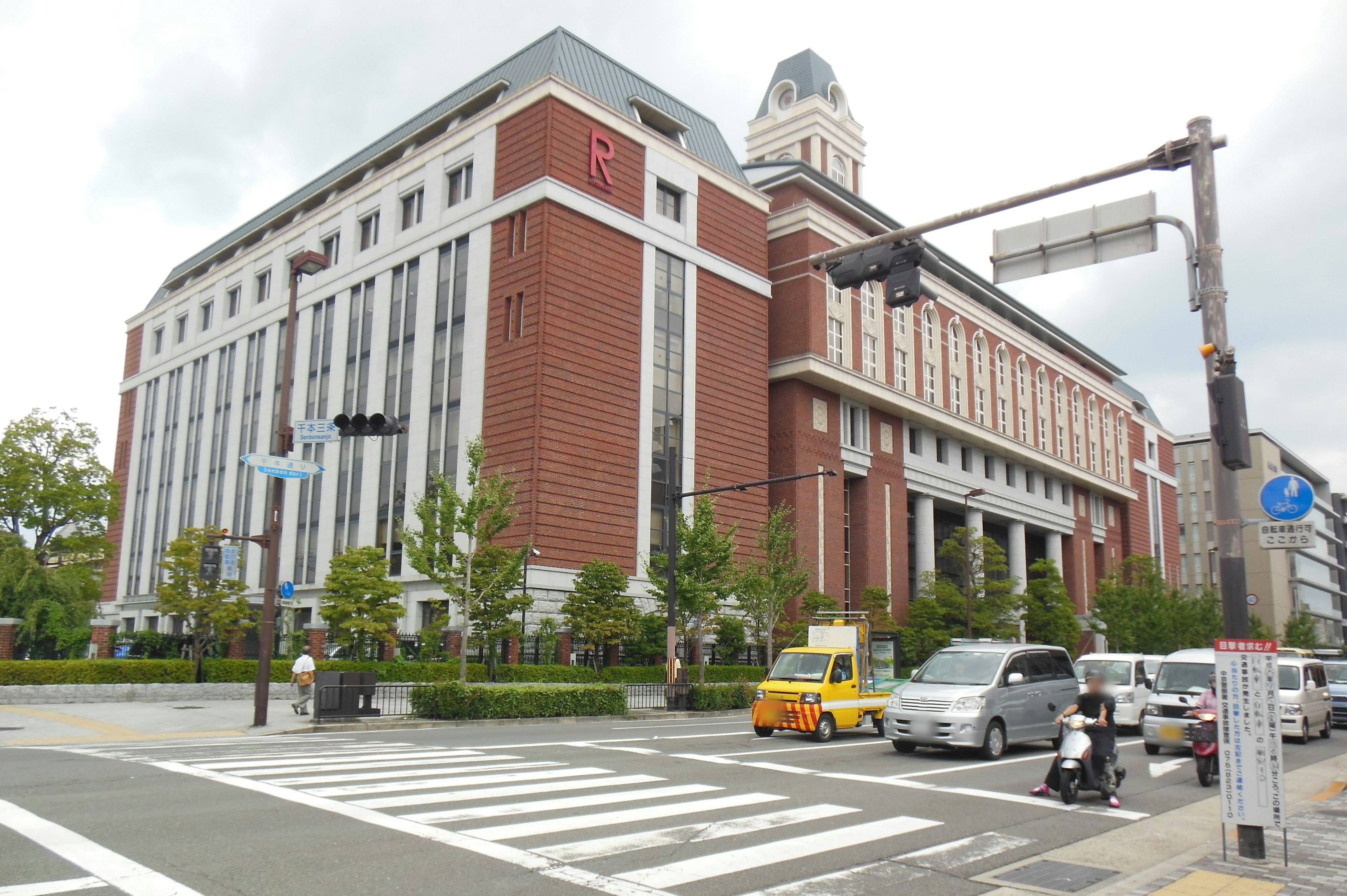 Intersection featuring a red brick building and surrounding greenery