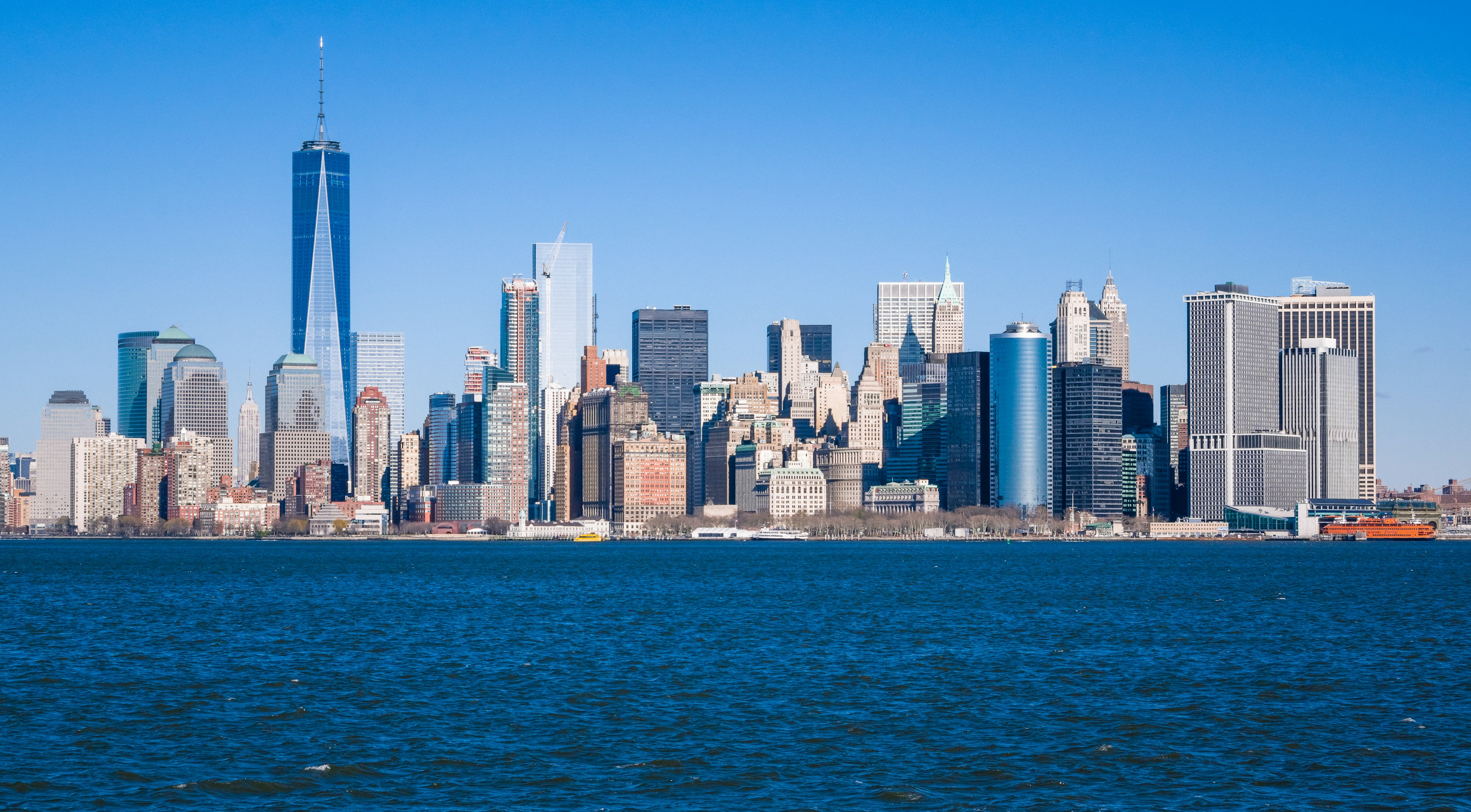 New York City skyline with skyscrapers and clear blue sky over the water