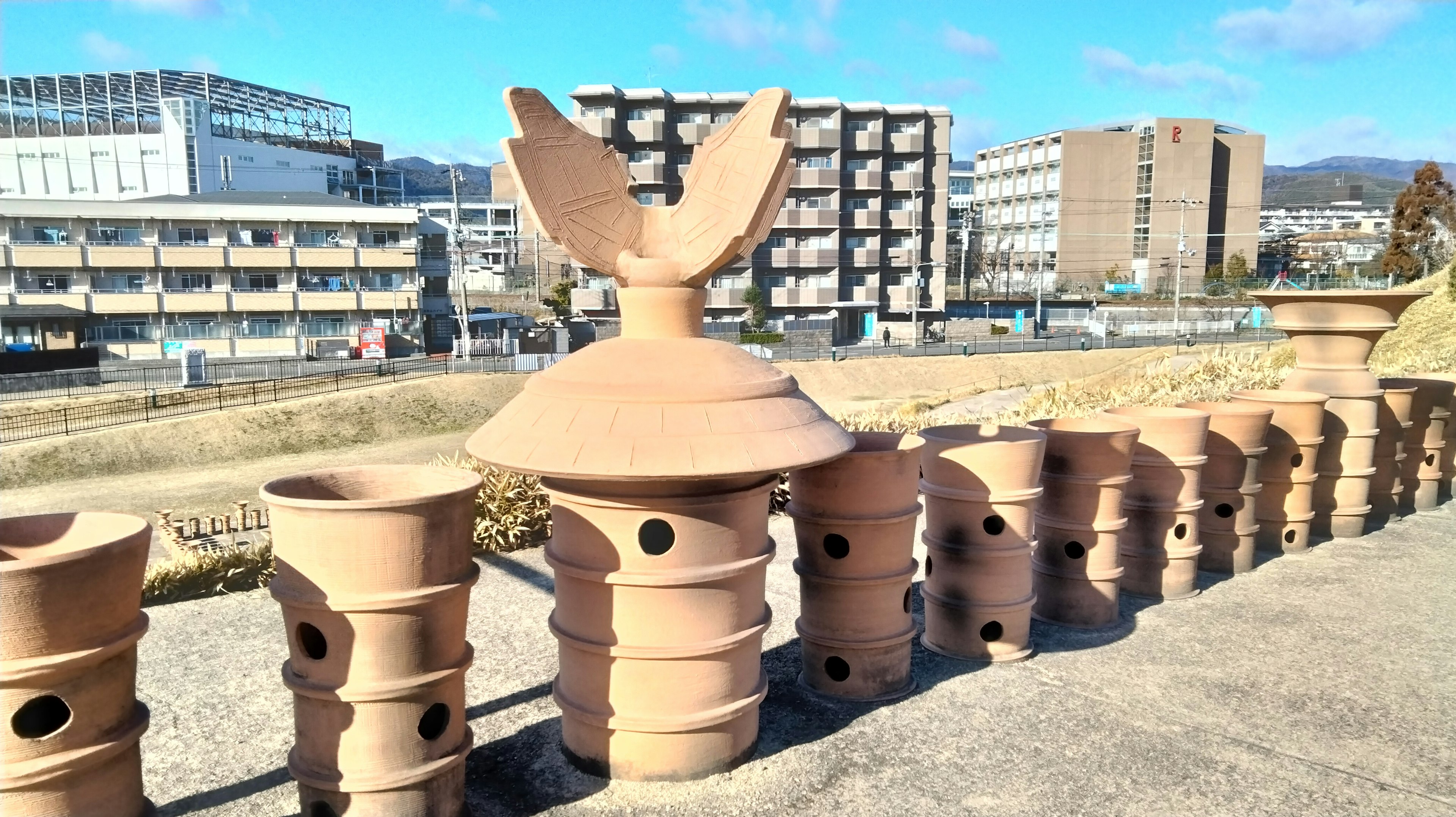 Outdoor display of unique ceramic sculptures with buildings in the background