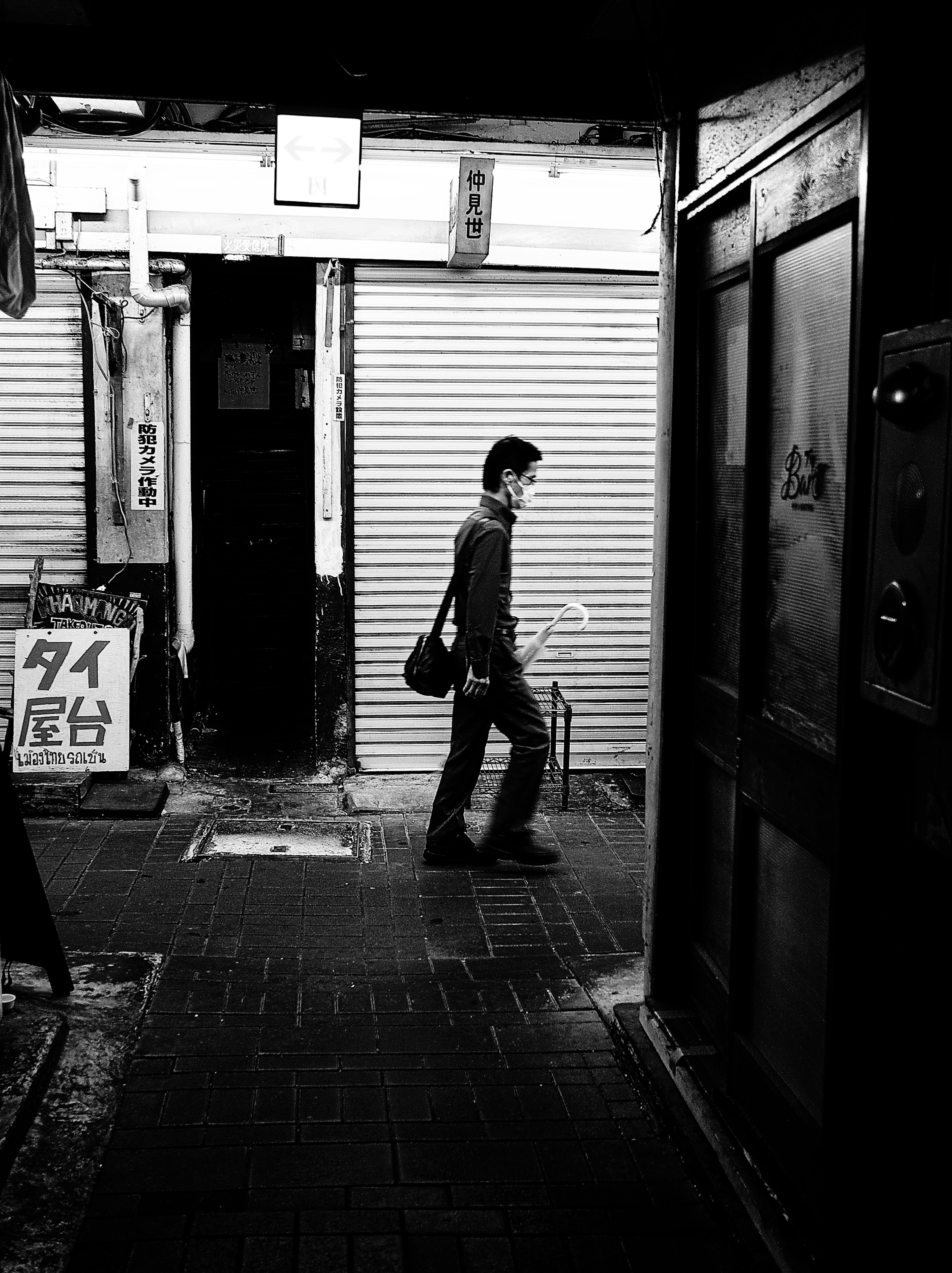 Un hombre caminando por una escena de calle en blanco y negro en una atmósfera tranquila