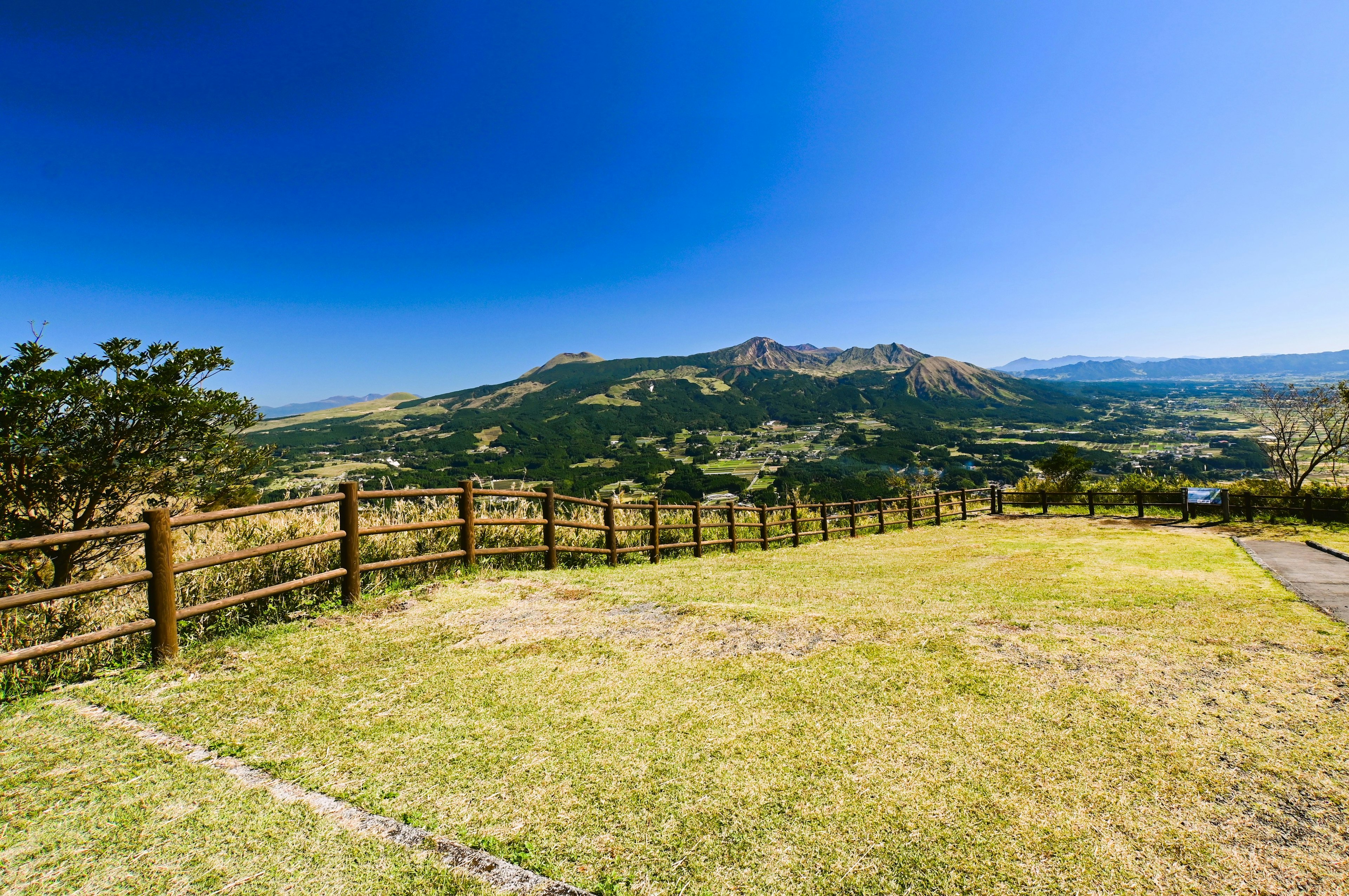 青空の下に広がる草原と山々の風景