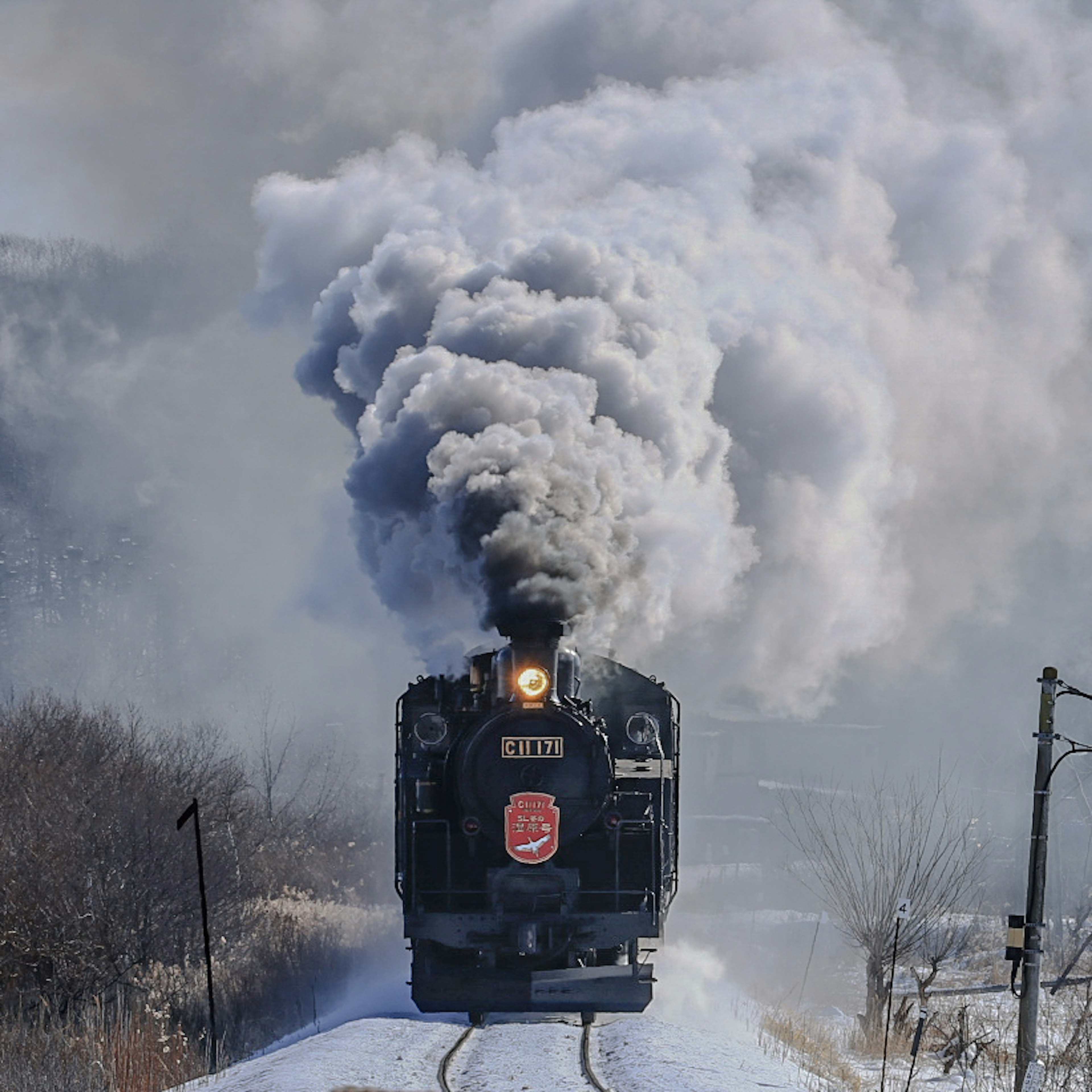 Steam locomotive moving through snow with smoke billowing