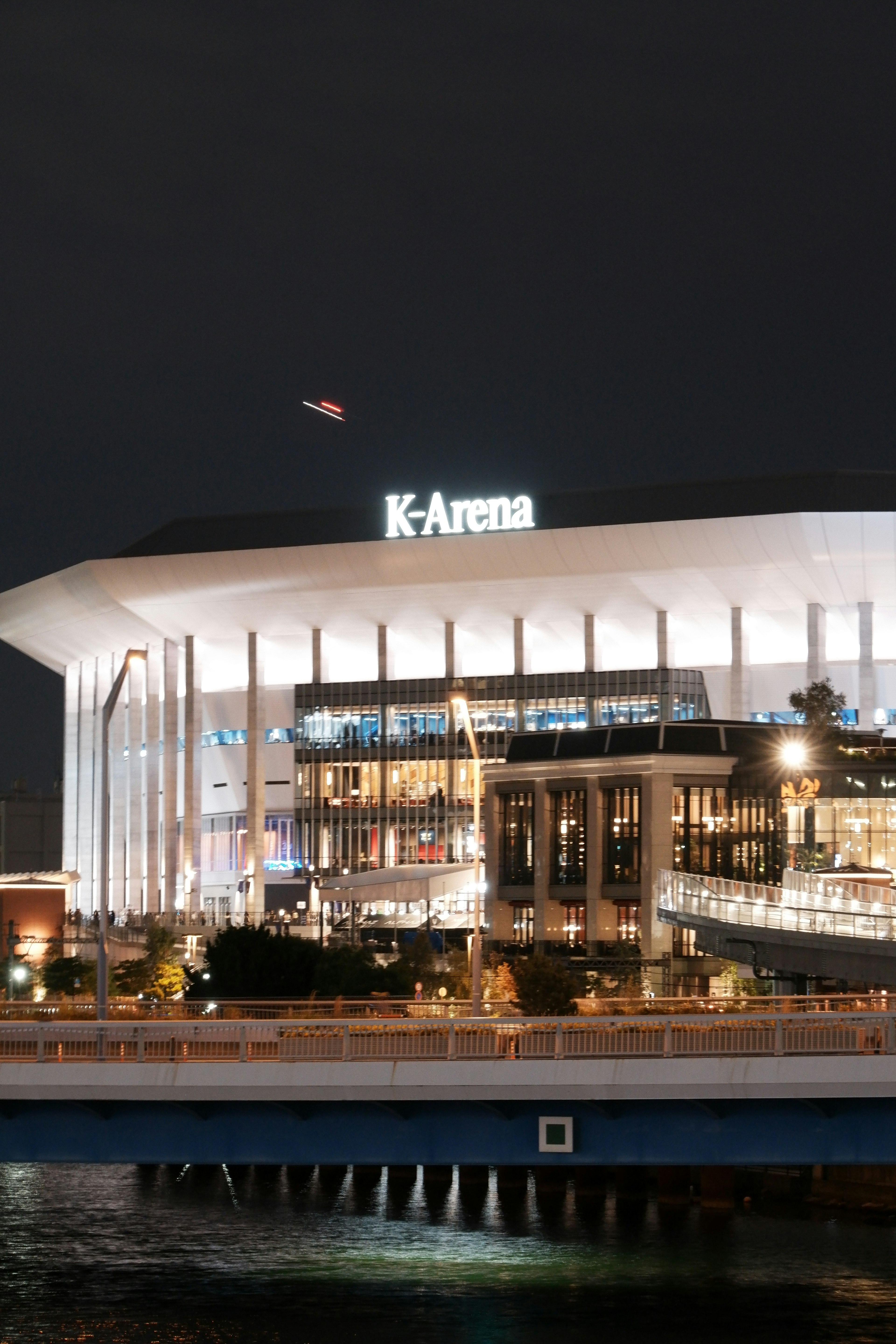 Vue nocturne du K-Arena mettant en valeur son architecture