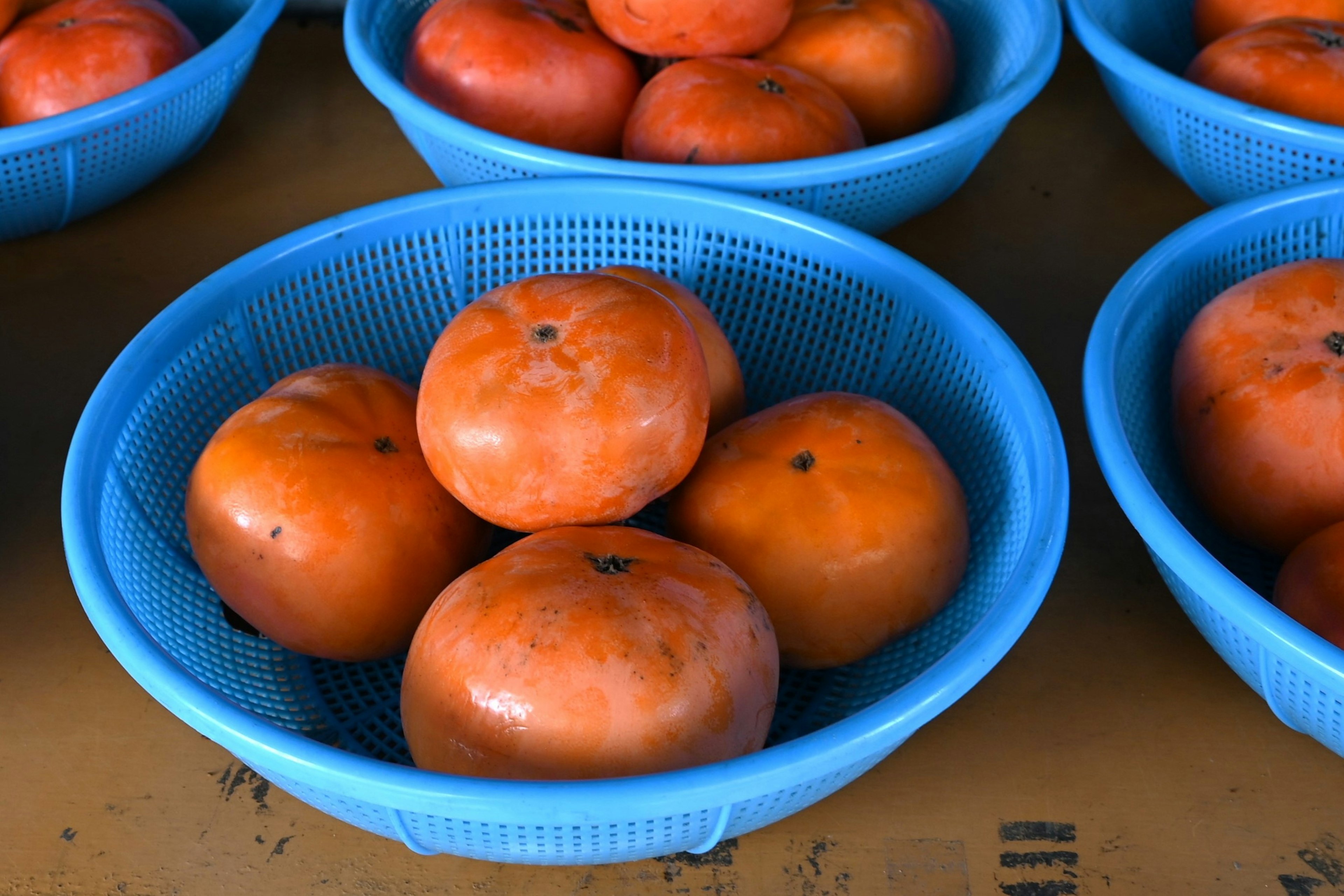 Kakis dans des paniers bleus sur une table de marché