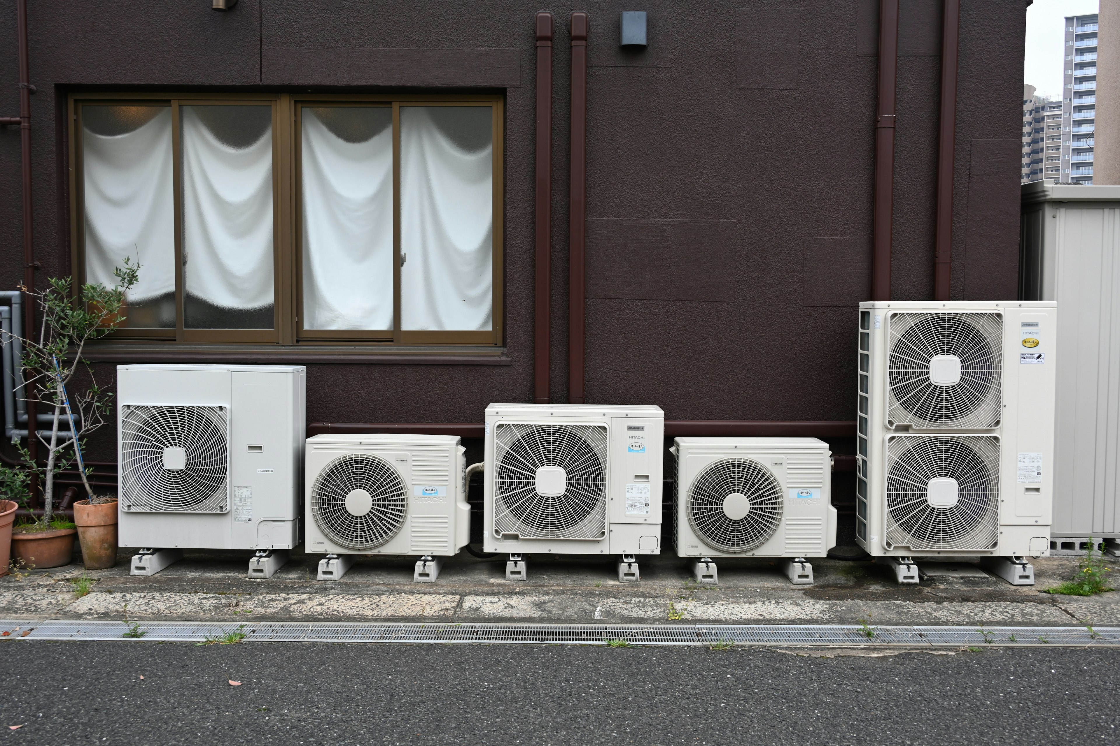 Image of multiple air conditioning units lined up against a building wall