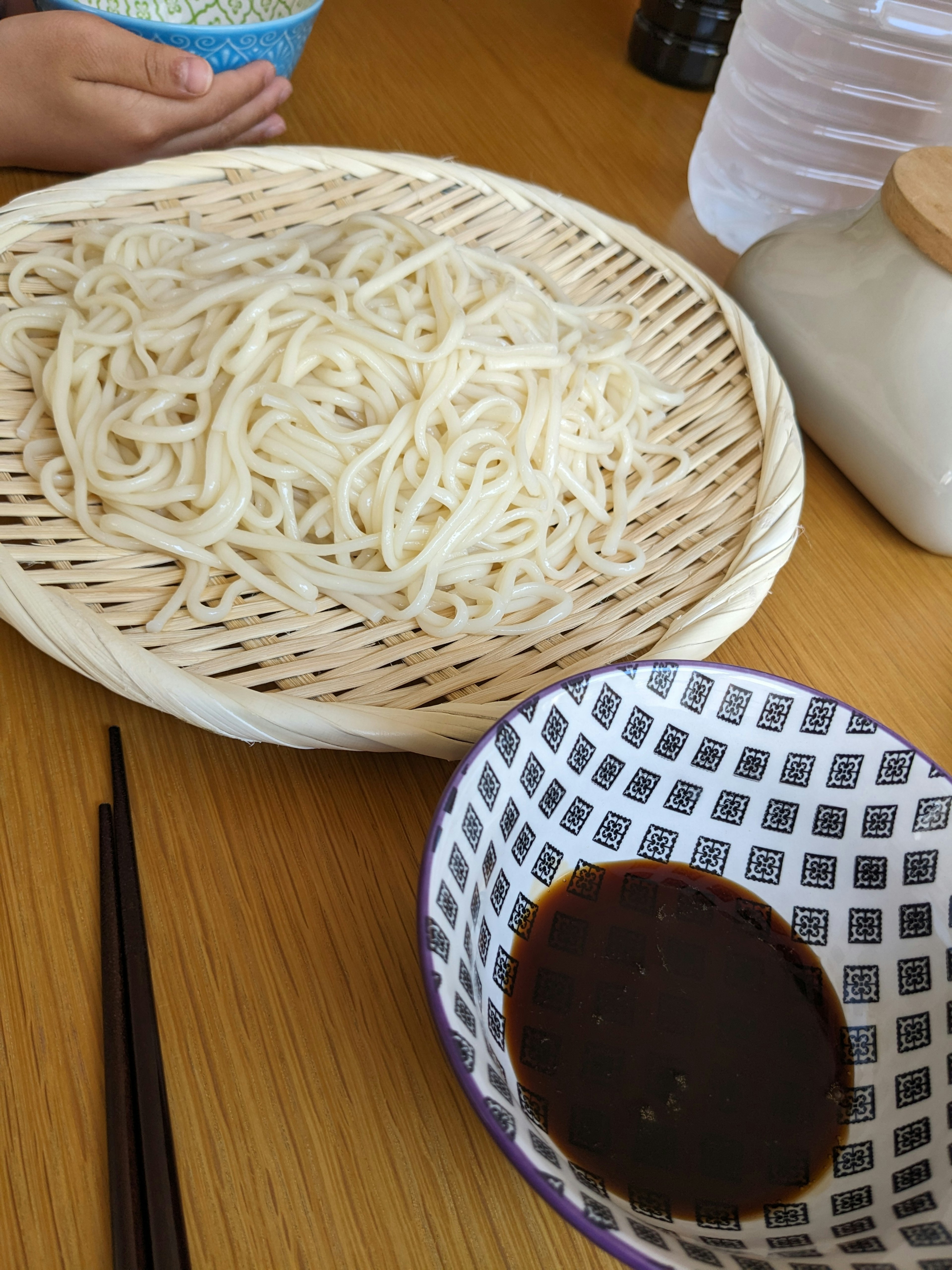 Une assiette de nouilles froides avec une sauce à tremper sur une table en bois