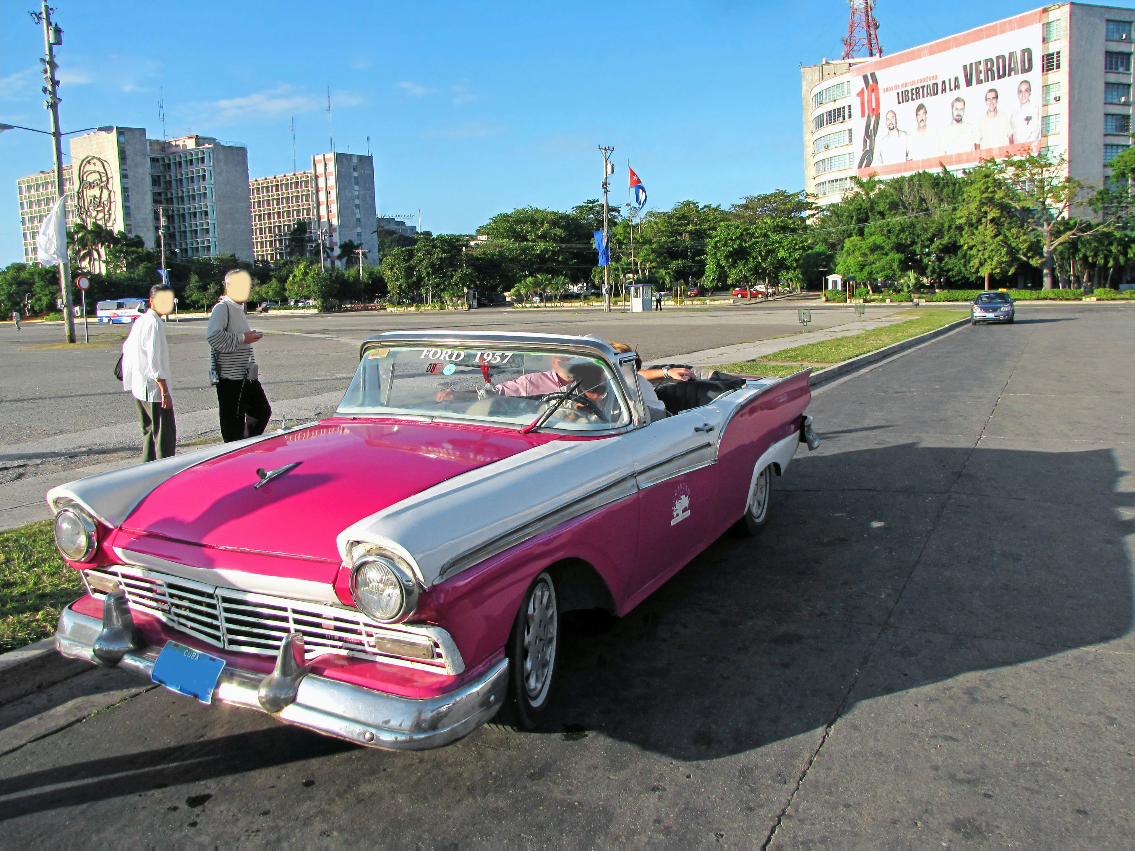 Une voiture classique rose et blanche garée dans la rue