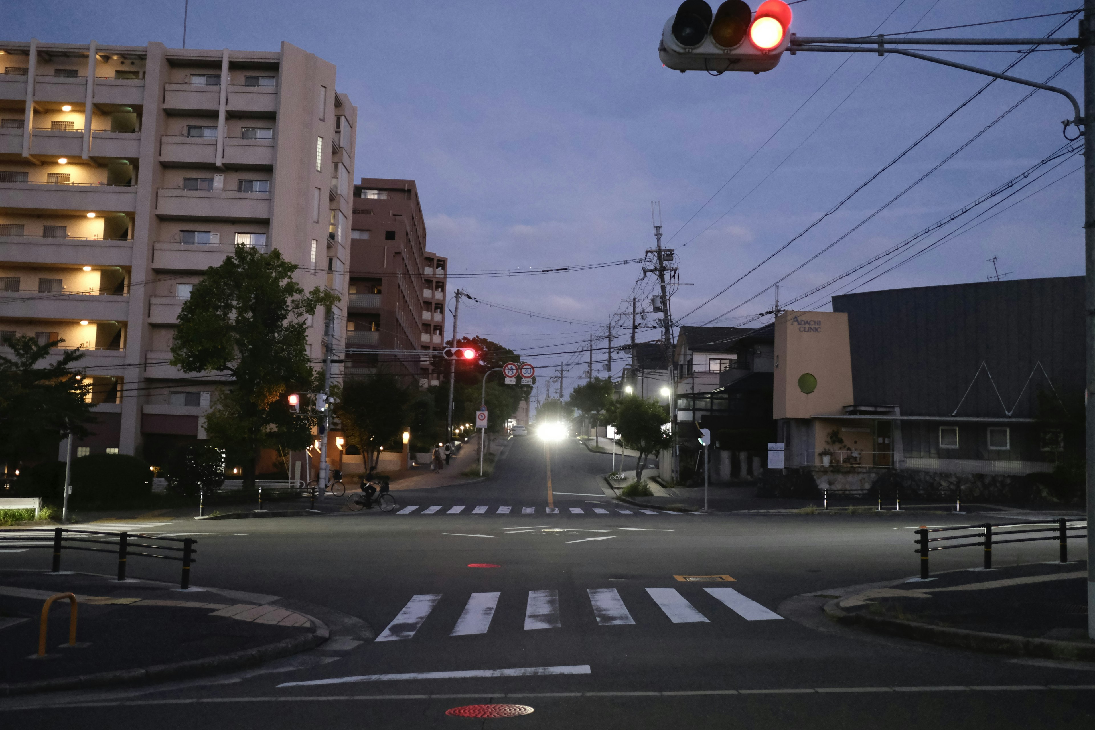 Street corner at night with a red traffic light and crosswalk