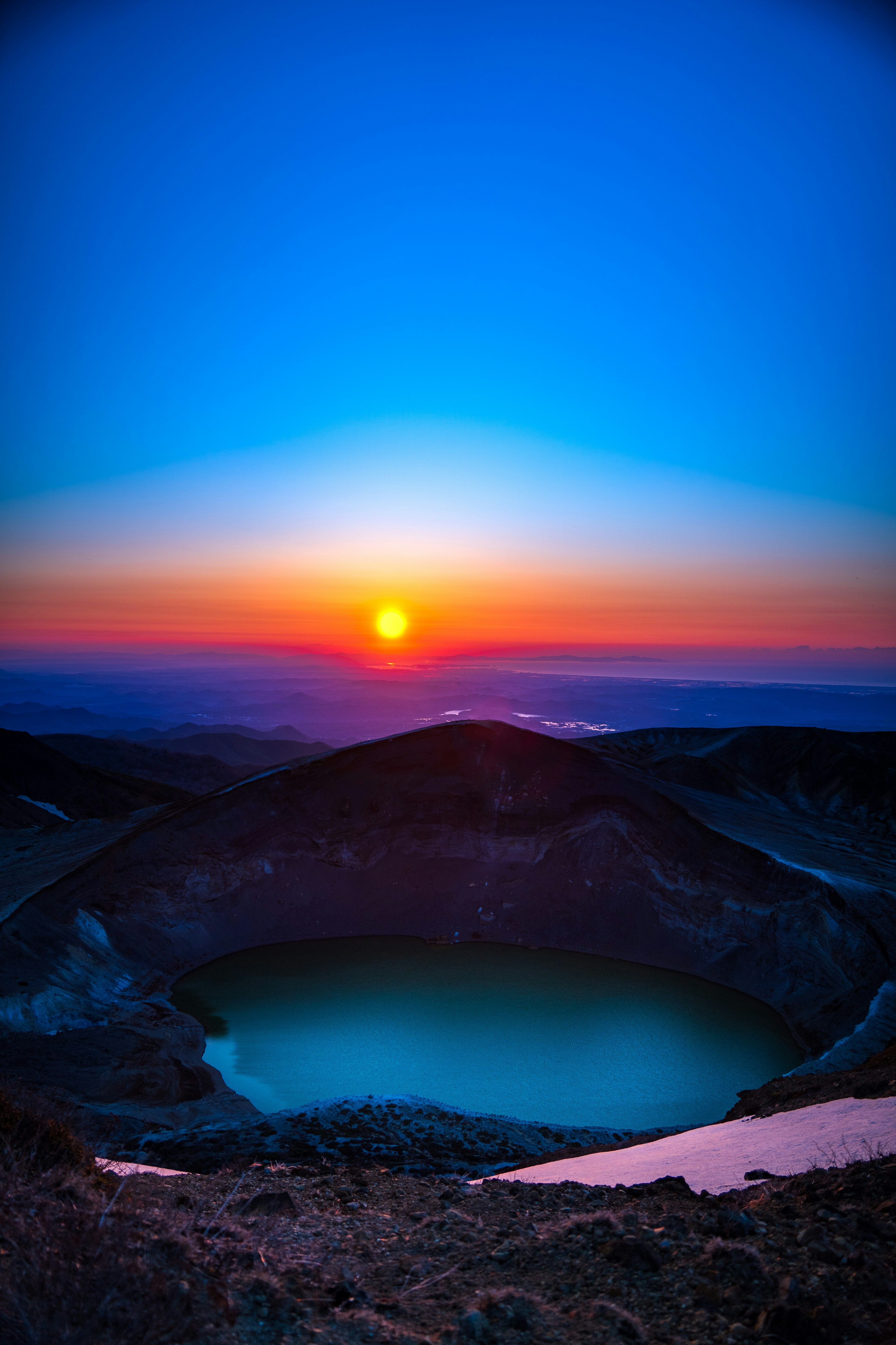 Vibrant sunset over a volcanic crater with a turquoise lake