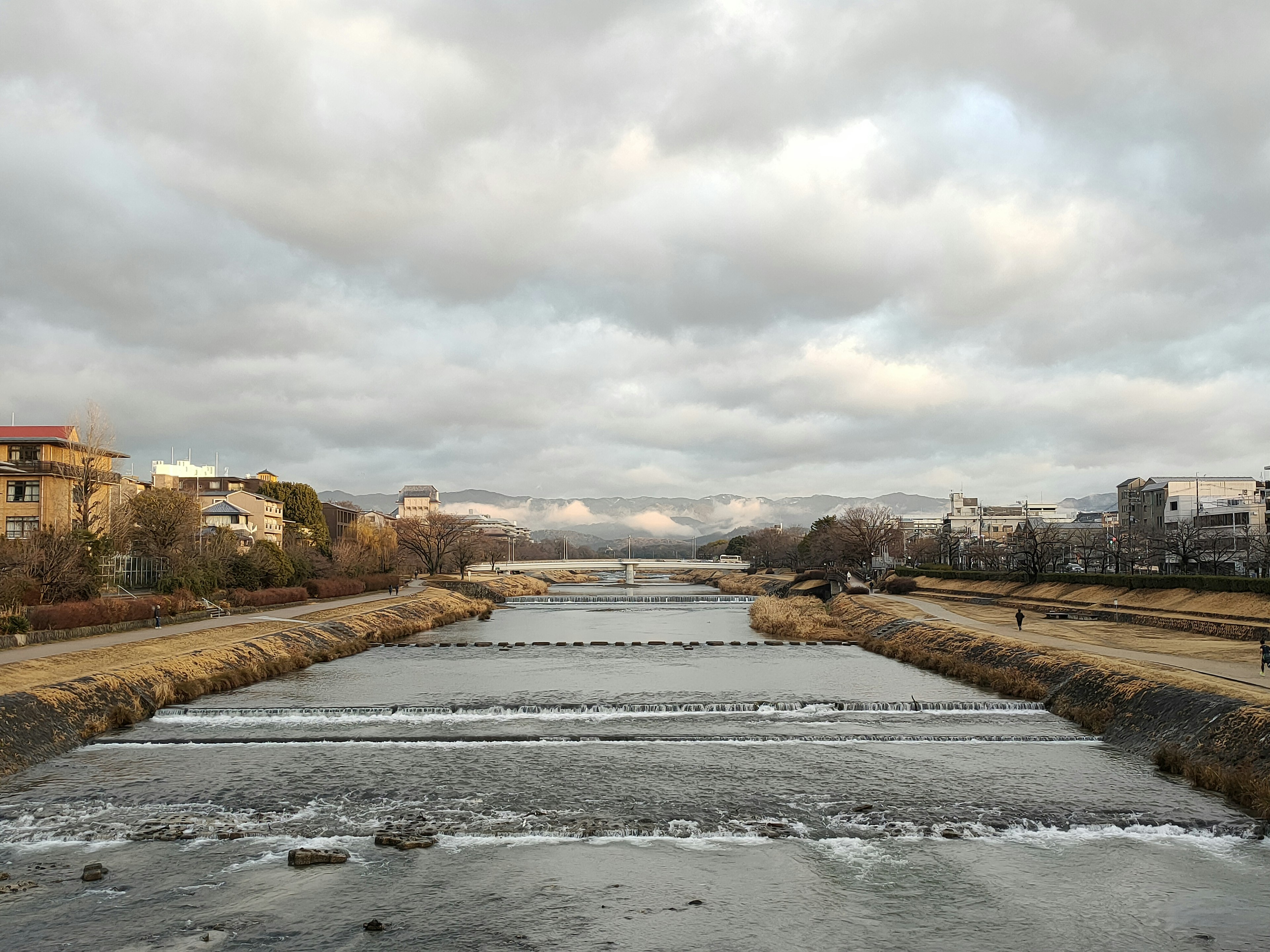 Pemandangan sungai tenang dengan langit mendung