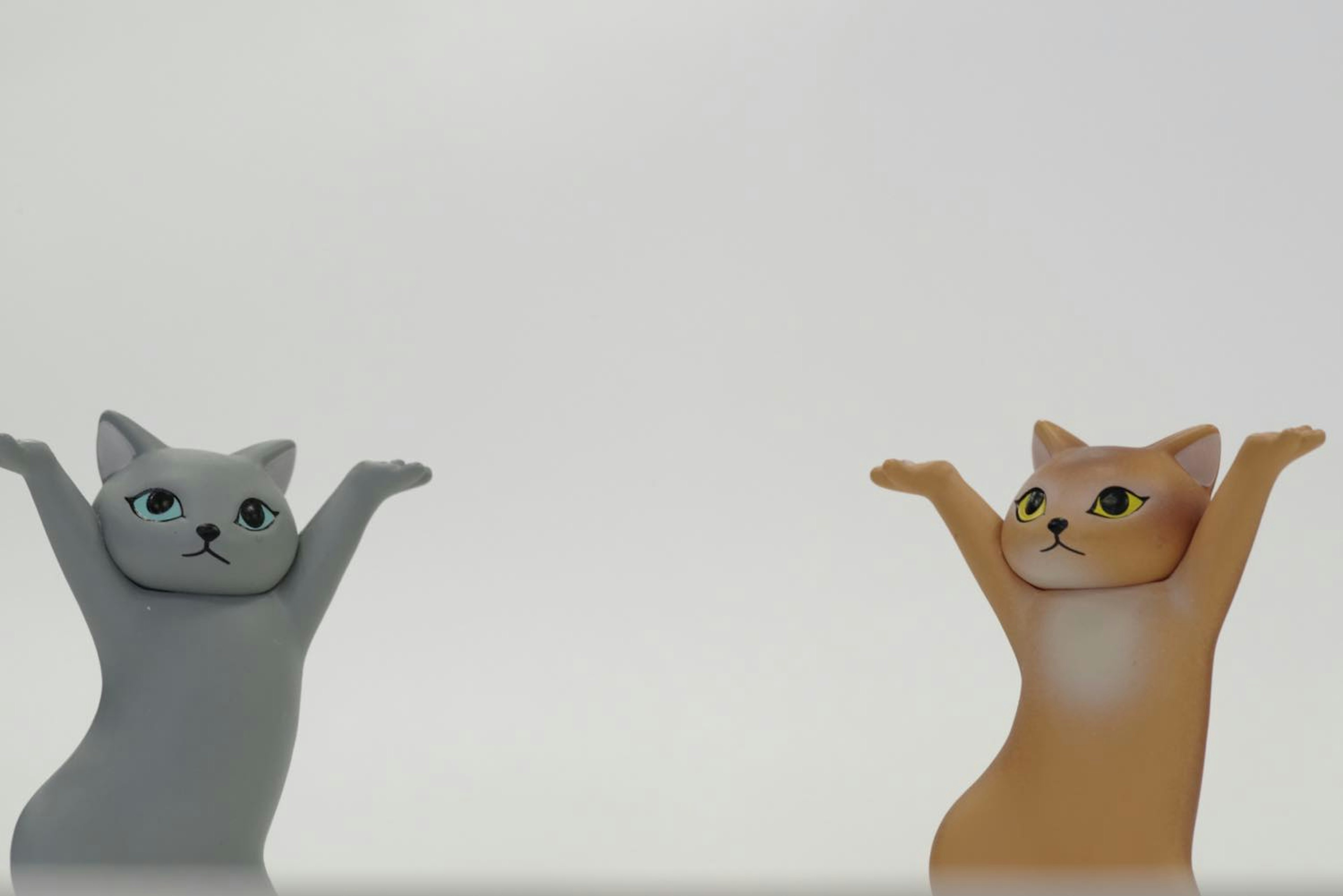 灰色とオレンジの猫のフィギュアが両手を上げている