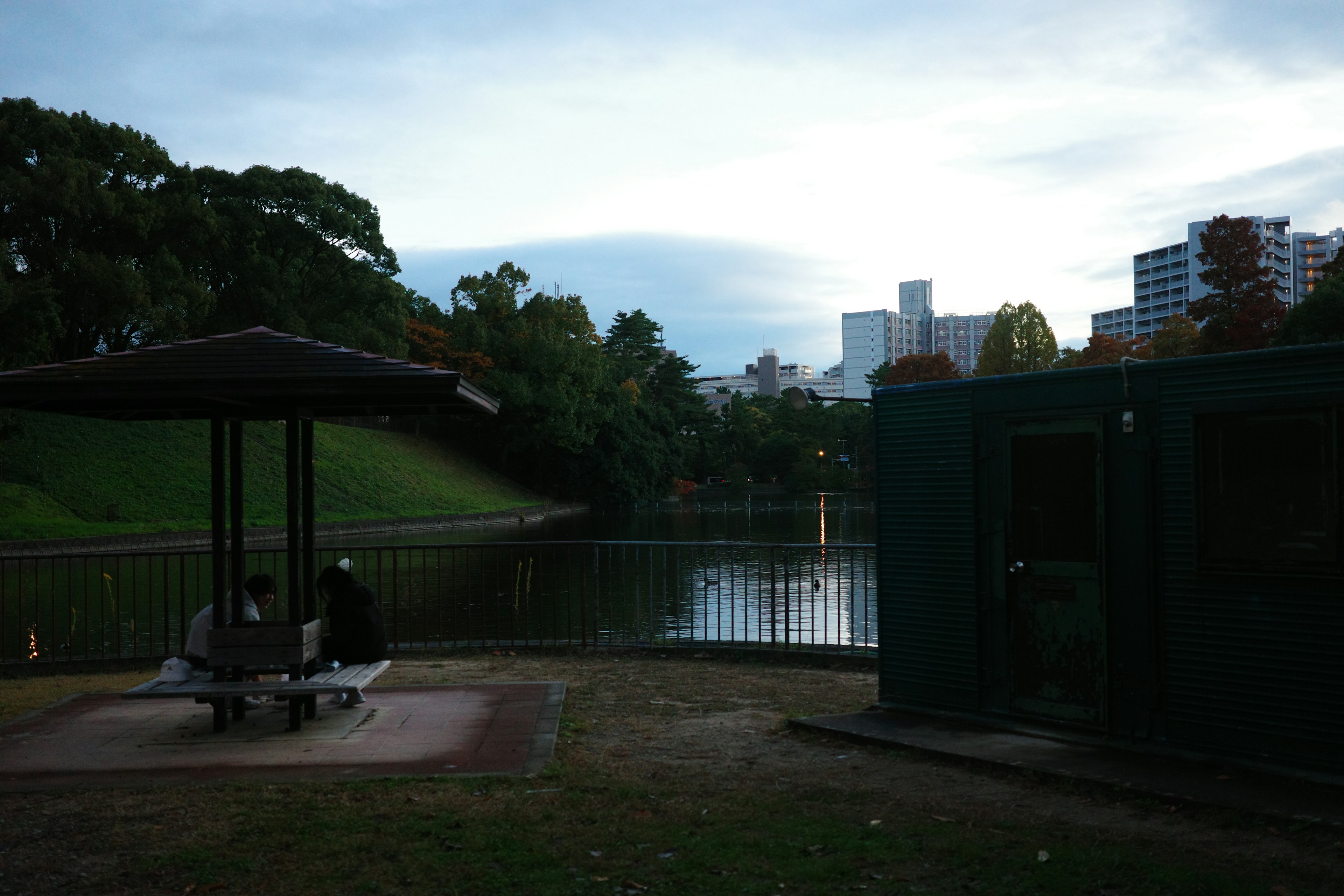 Una vista de un pabellón y un banco cerca de un estanque del parque