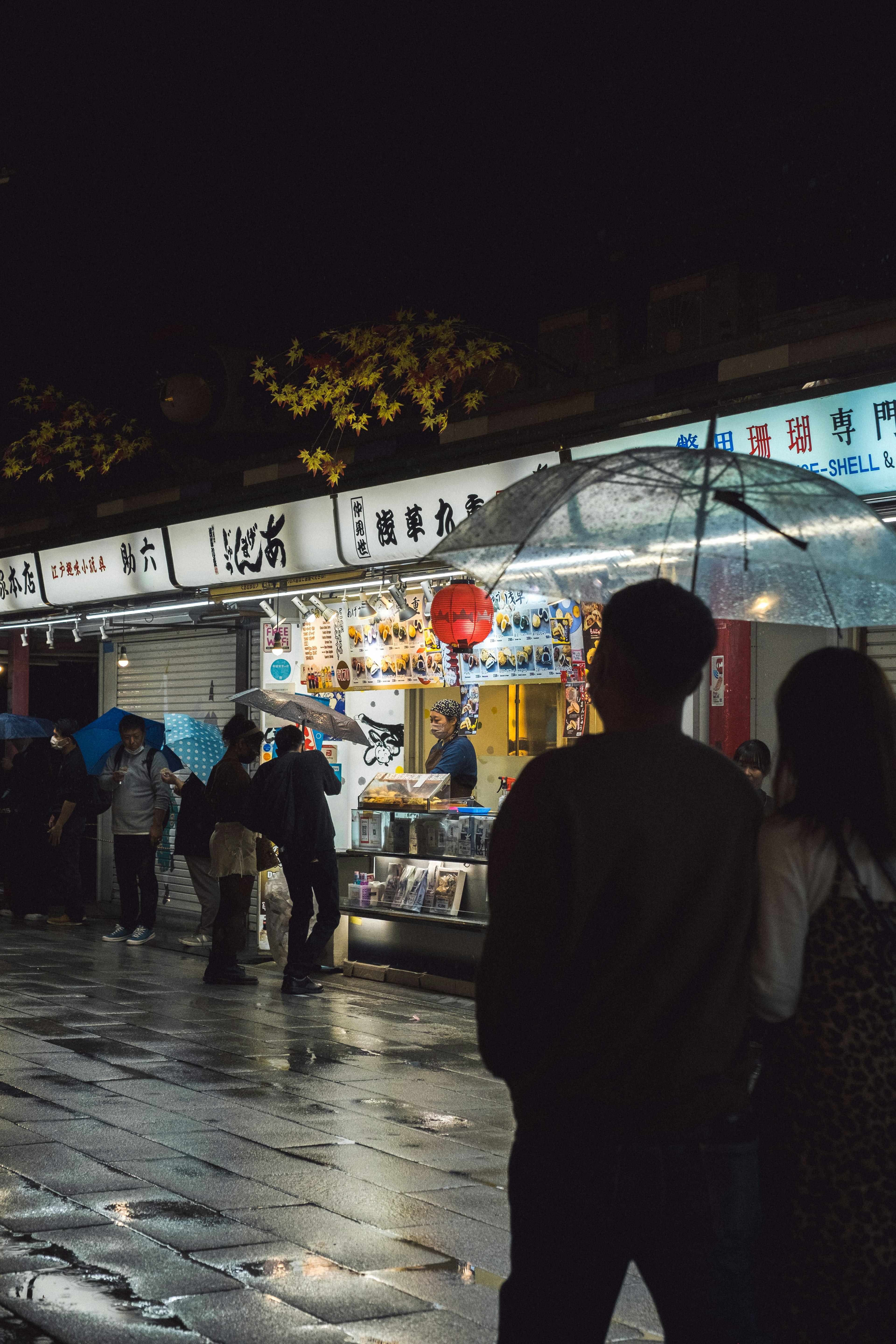 Escena de mercado nocturno con puestos de comida y personas