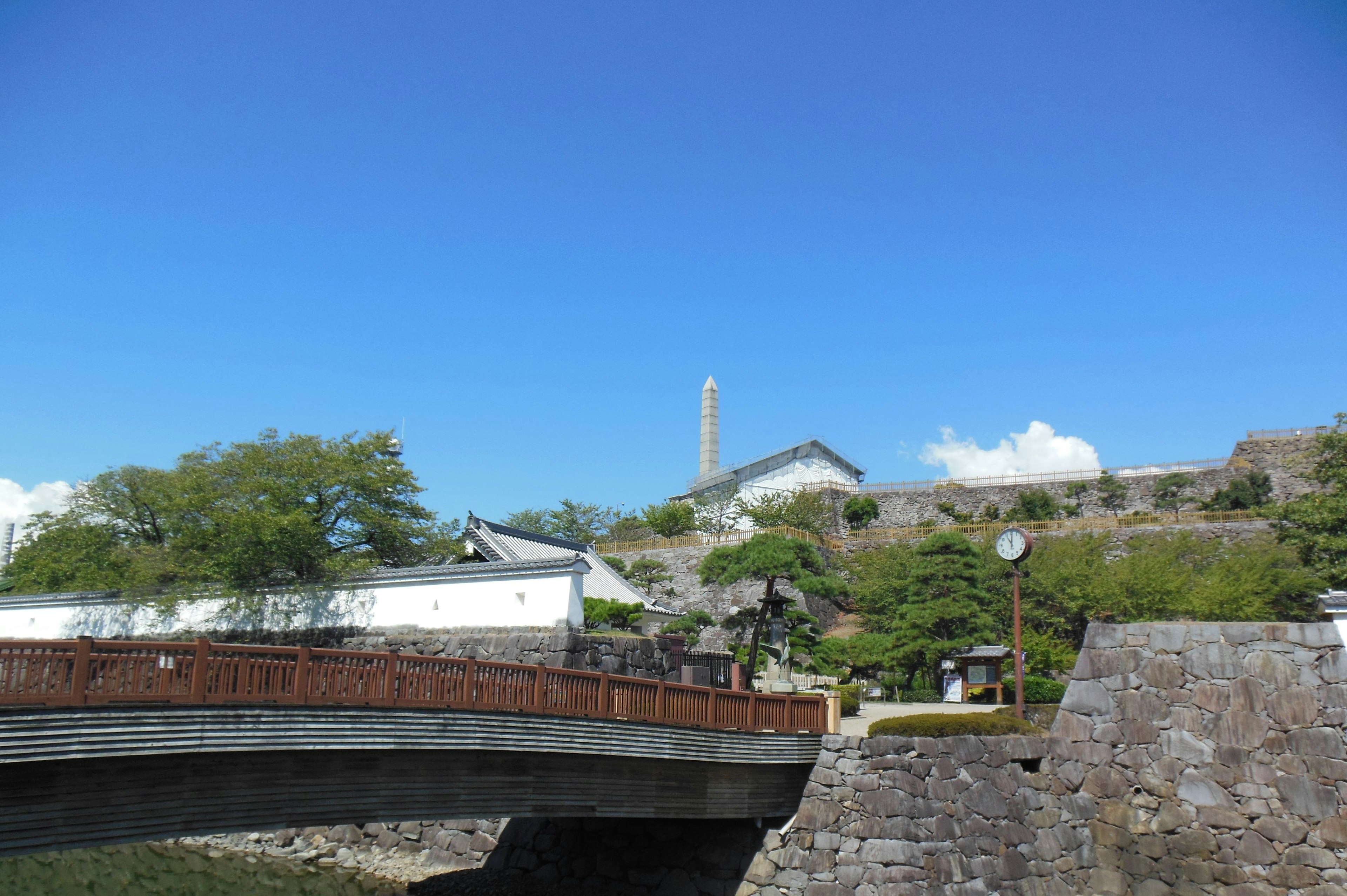 Puente de piedra y muralla del castillo bajo un cielo azul