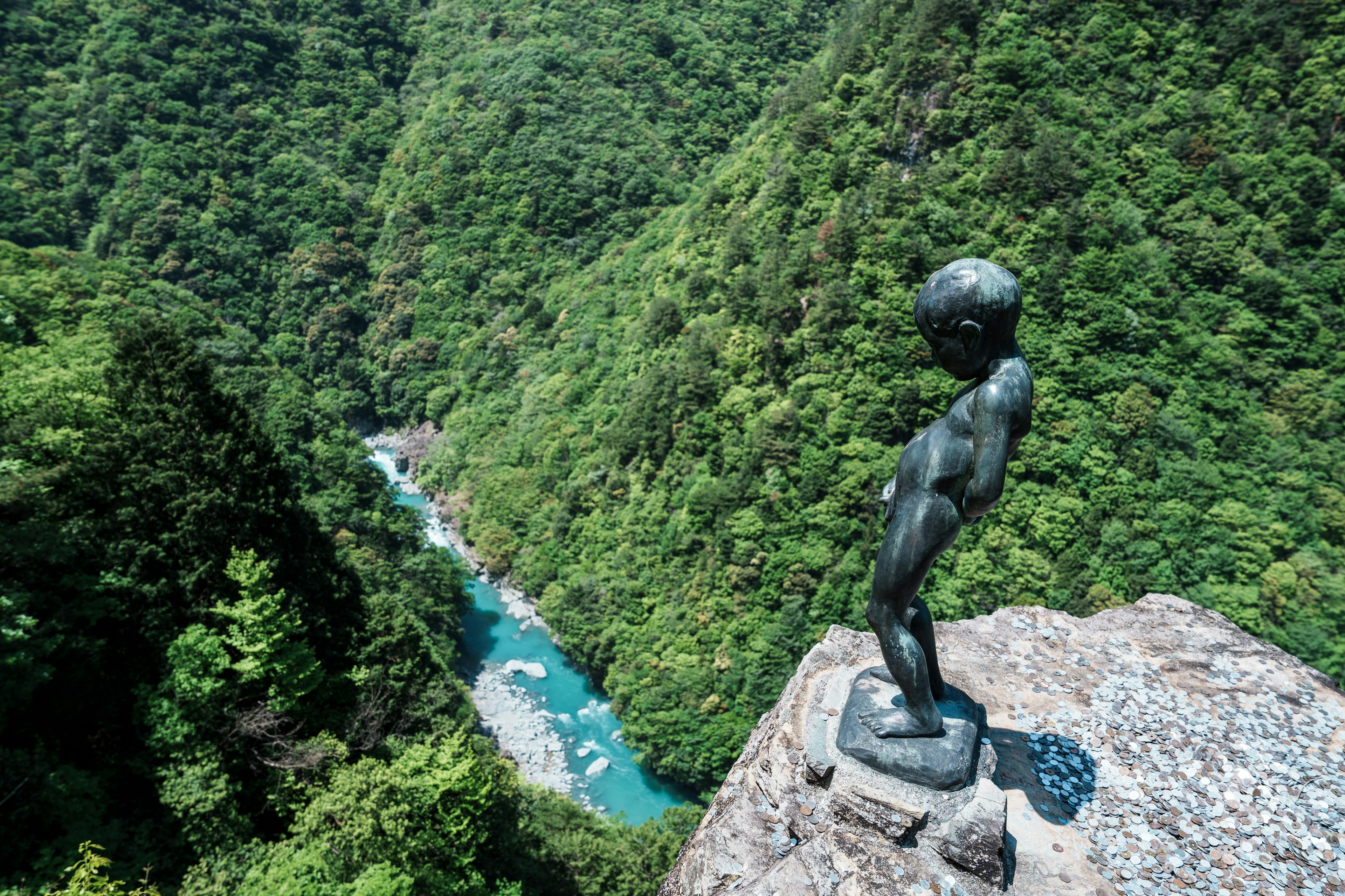 小青銅雕像俯瞰郁鬱蔥蔥的綠色山脈和藍色河流