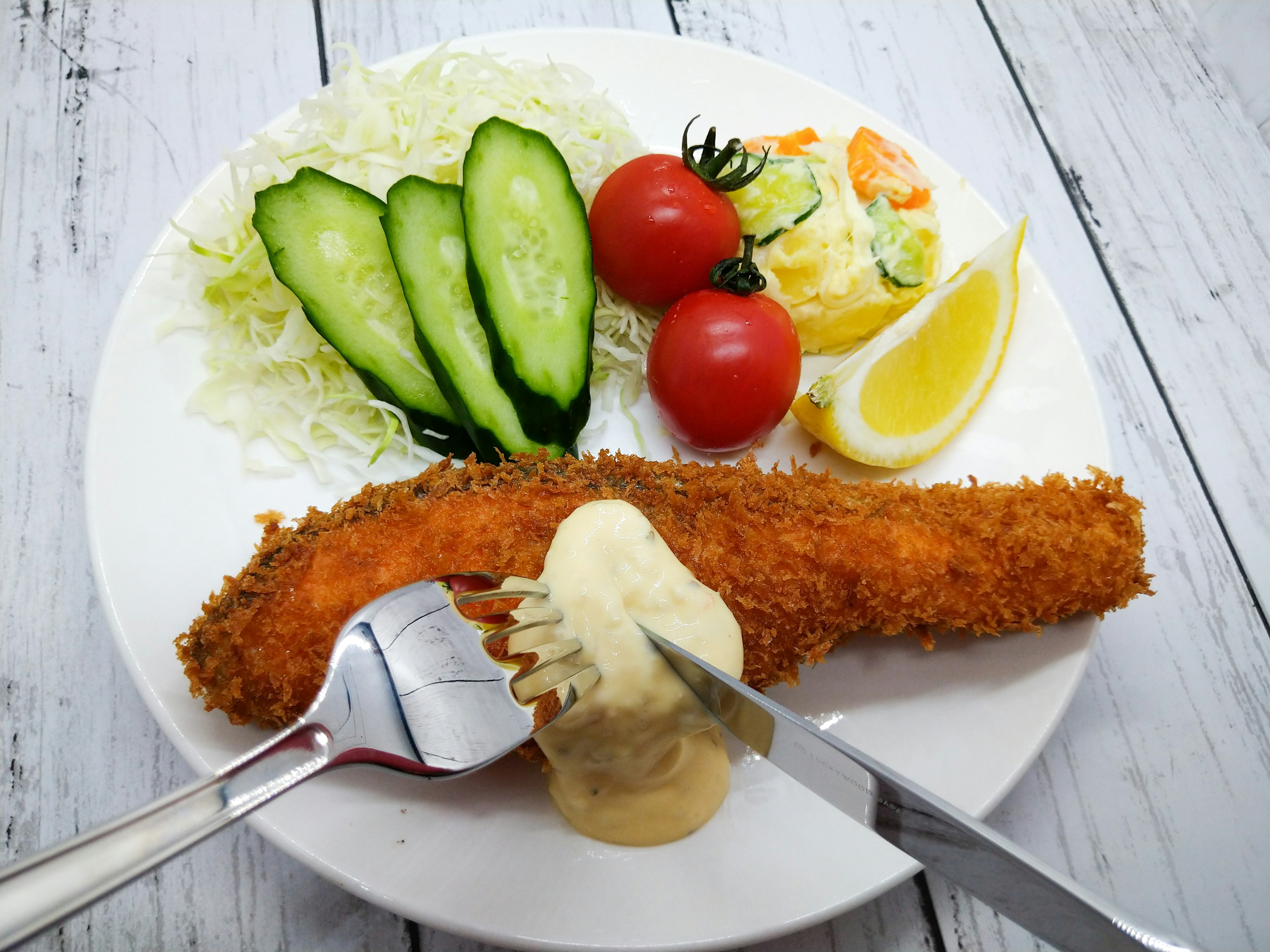 Filete de pescado empanizado con ensalada y vegetales en un plato