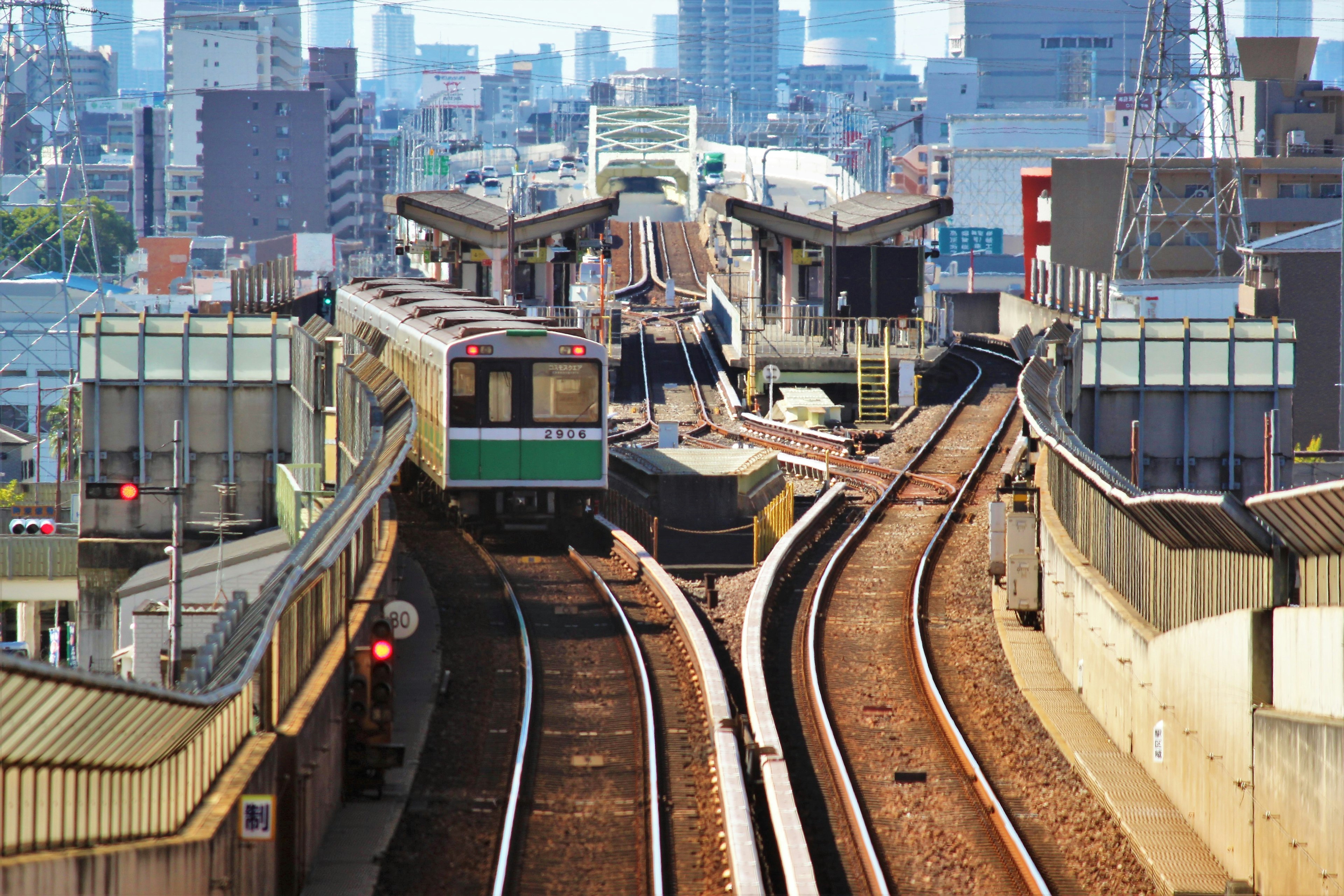 Urban train station with intersecting tracks and a train stopping