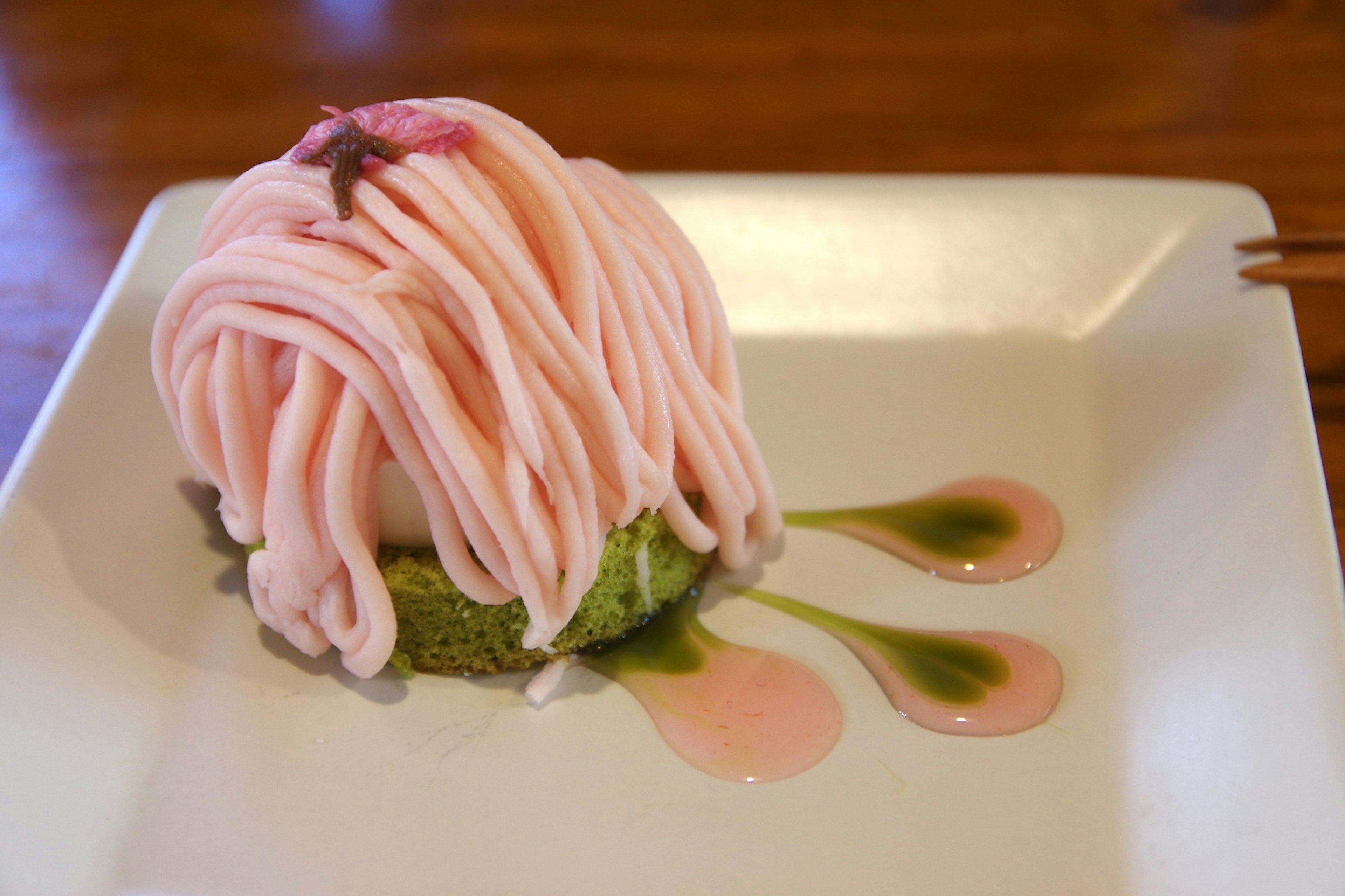 Pastel mont blanc rosa en un plato verde de matcha con salsa alrededor