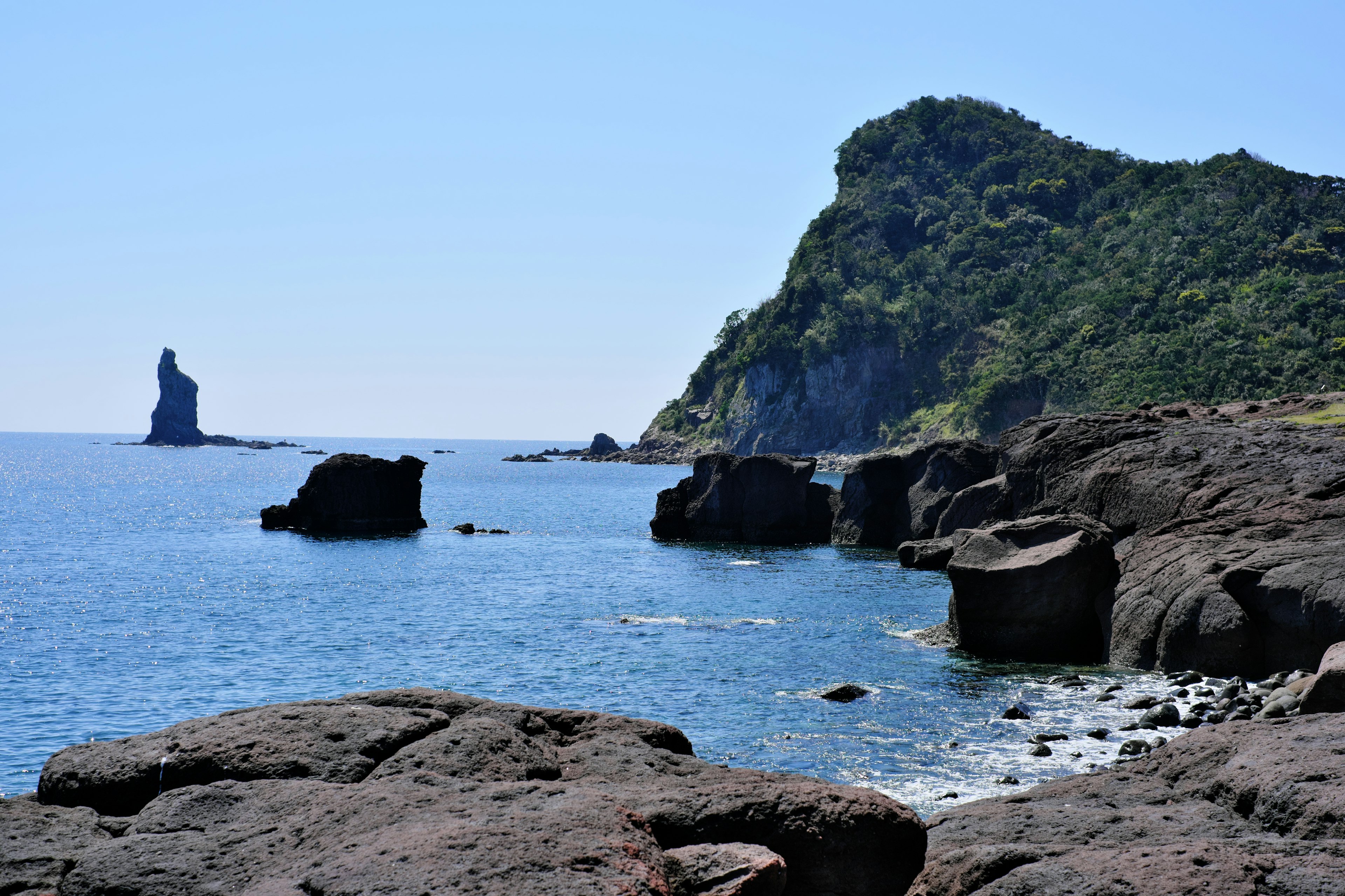 Vista costiera panoramica con formazioni rocciose e cielo blu chiaro