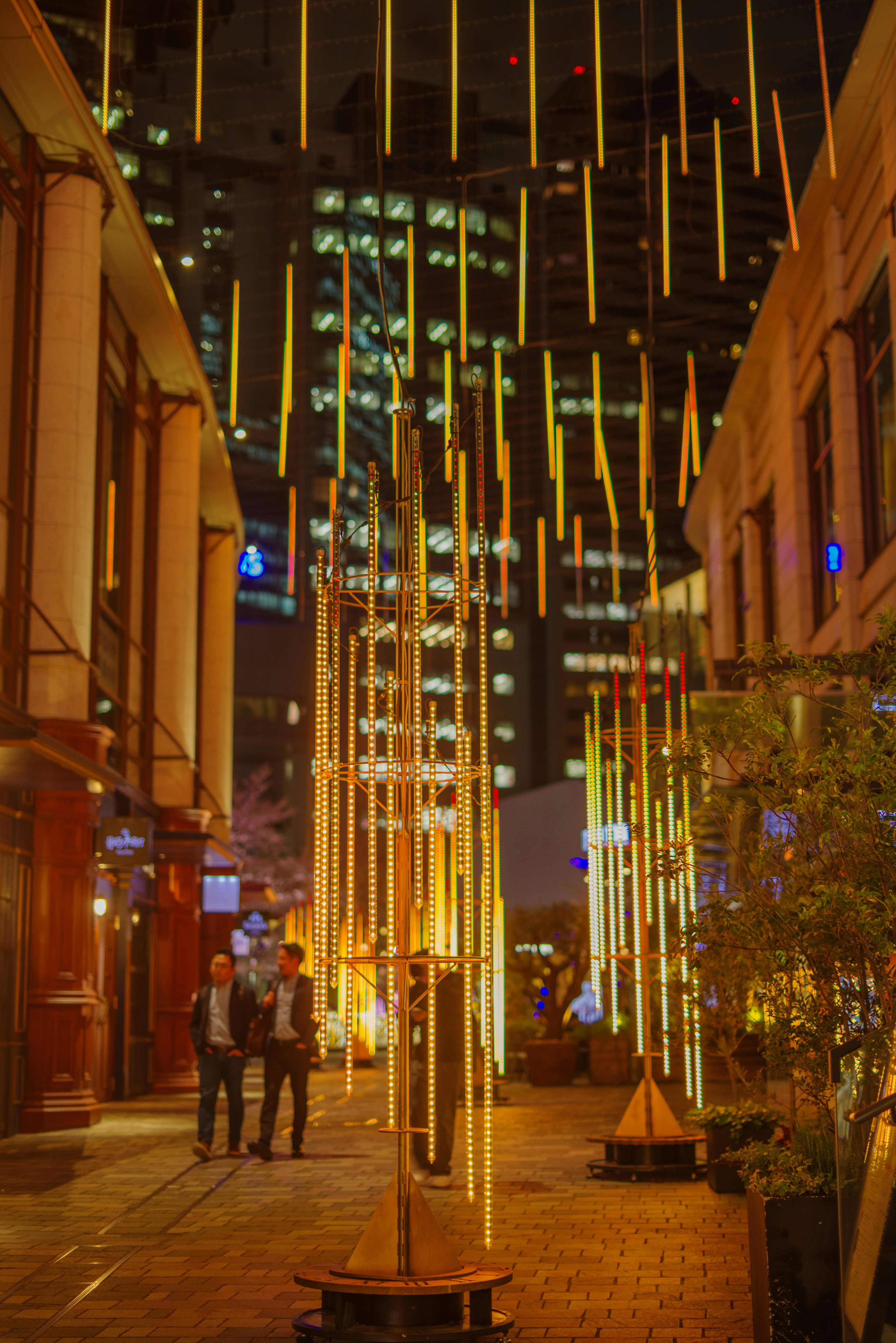 Beleuchtete vertikale Lichtinstallationen hängen in einer Stadtstraße bei Nacht